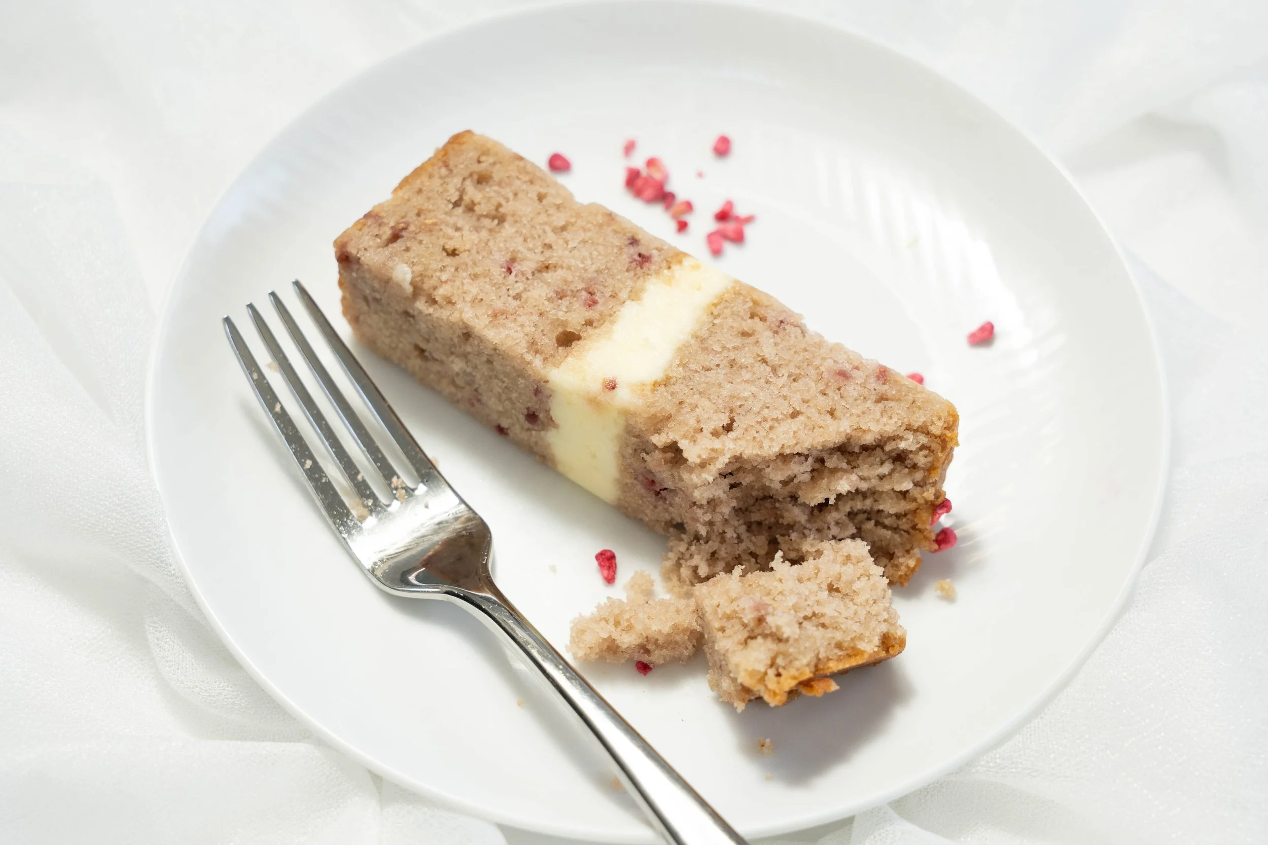 A slice of cake with a cream and raspberry filling on a white plate