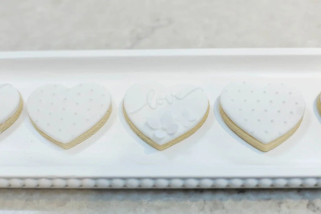 Heart-shaped cookies decorated with white icing on a white tray.