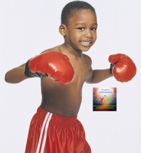 Young boy wearing red boxing gloves and red shorts, smiling, standing with his arms raised in a boxing pose.