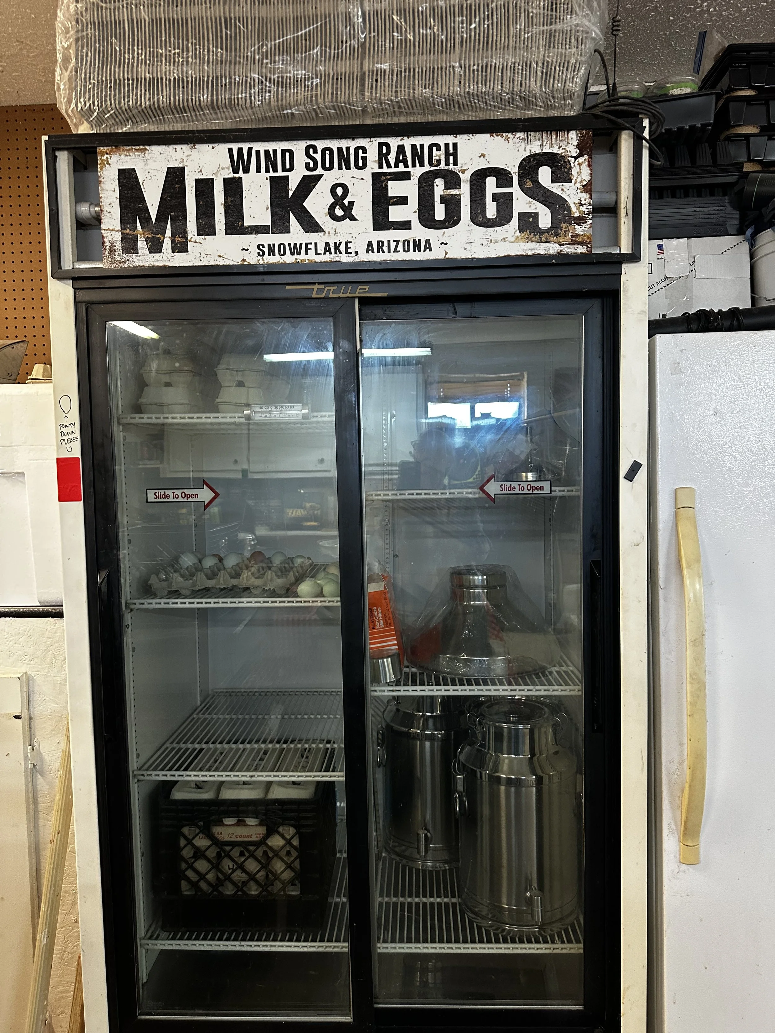Commercial refrigerator in ranch market with eggs, milk cans, strainer