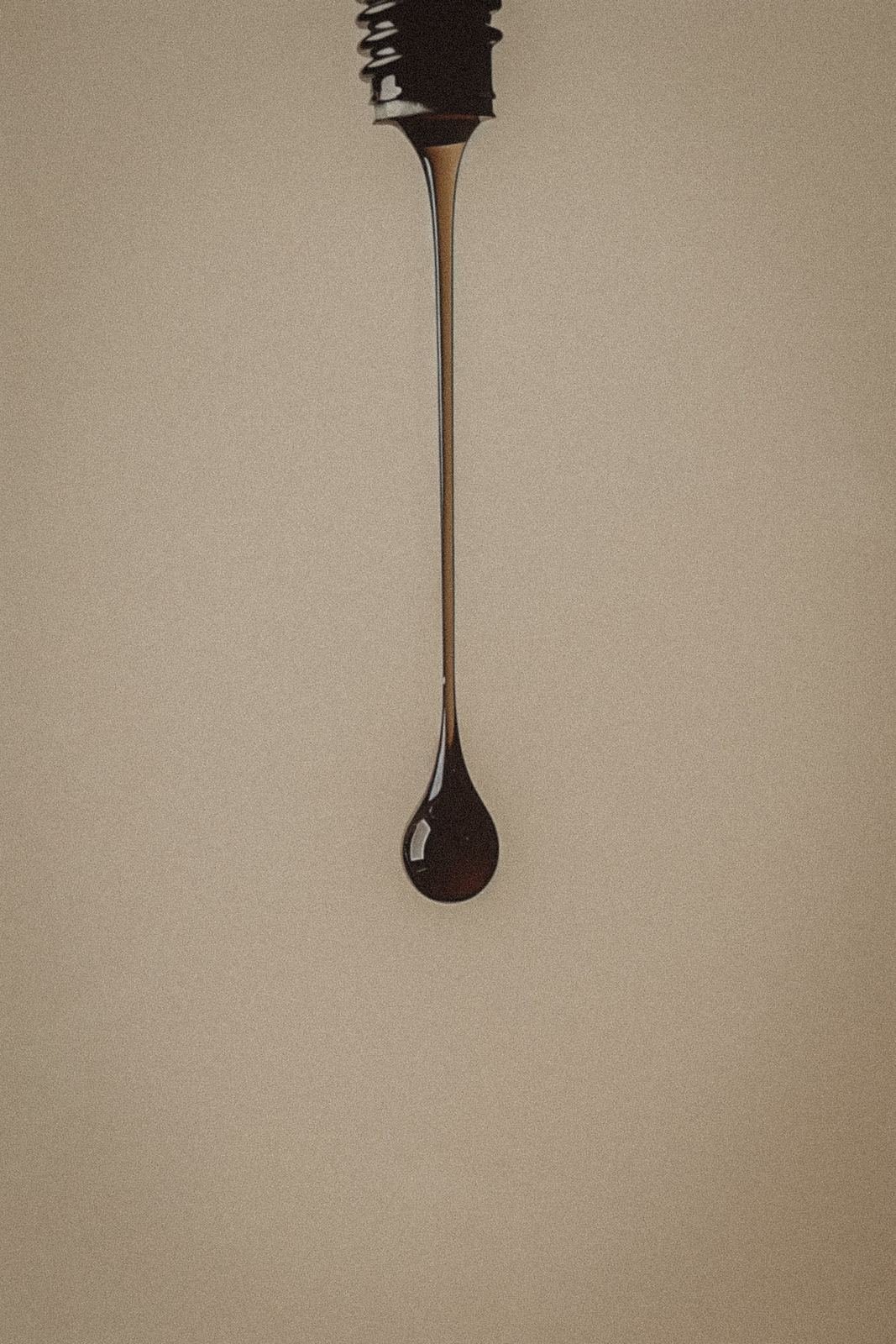 A single drop of dark liquid falling from a dropper