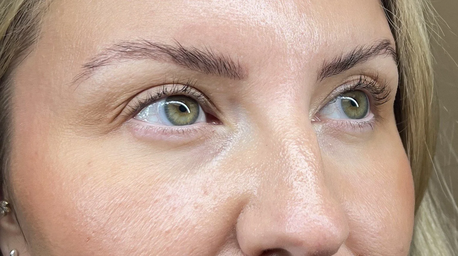 Close-up of a person's face focusing on the eyes, eyebrows, and part of the nose, with blonde hair and light skin.