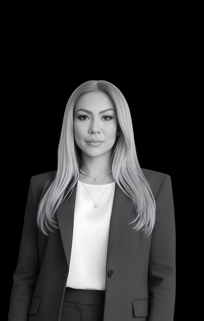 A professional woman with long, straight blonde hair wearing a dark blazer over a white blouse, standing against a black background.