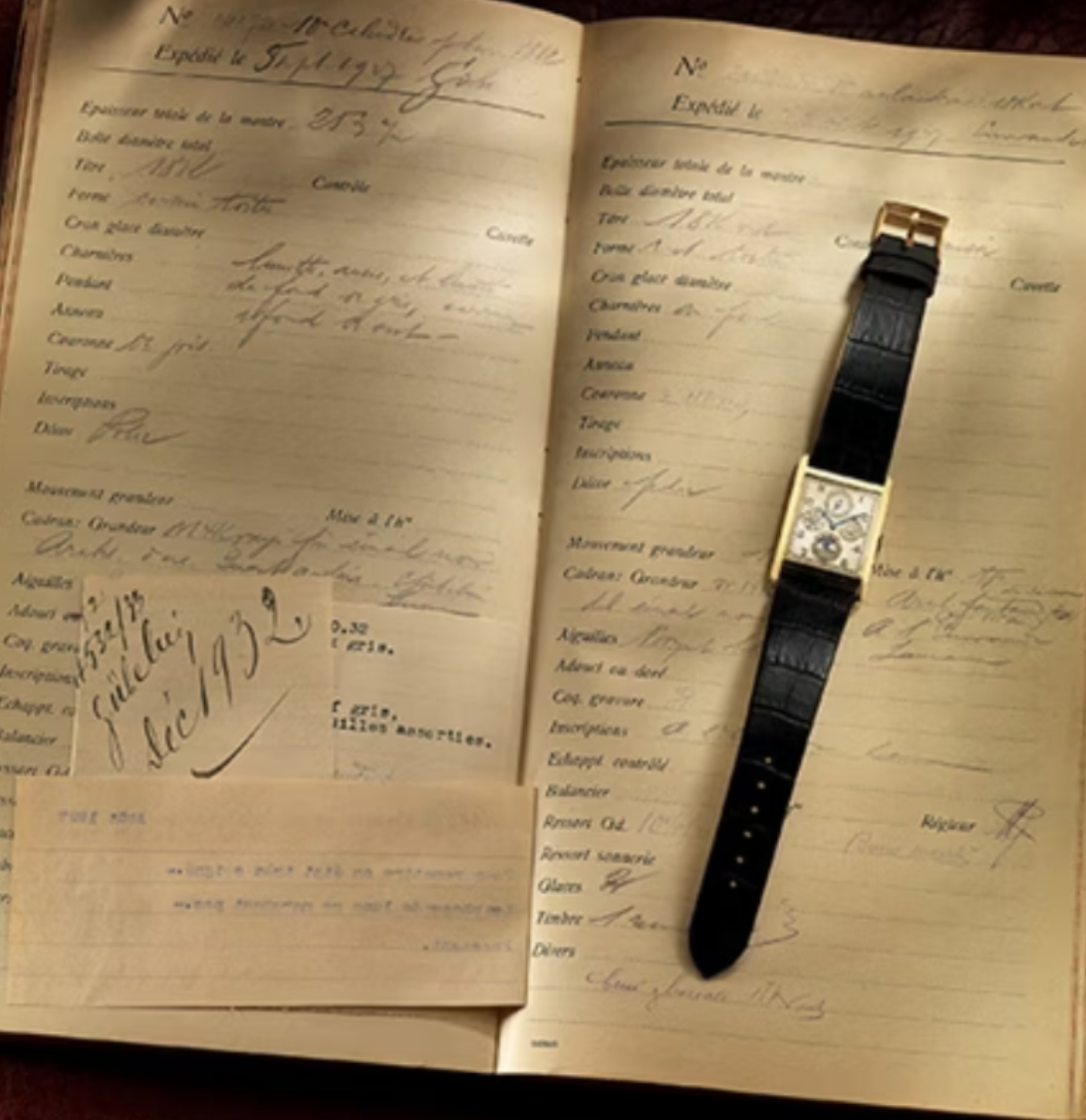 Open vintage ledger or notebook with handwritten notes in cursive, with a gold and black wristwatch resting on top of the right page.