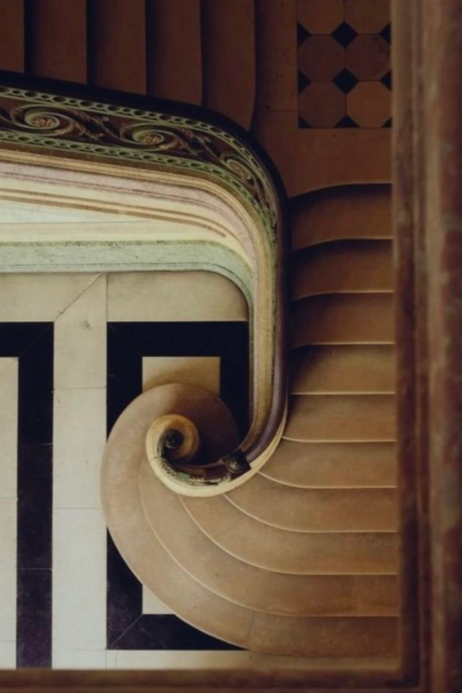 View from the top looking down a spiraling staircase with ornate details and patterned borders.