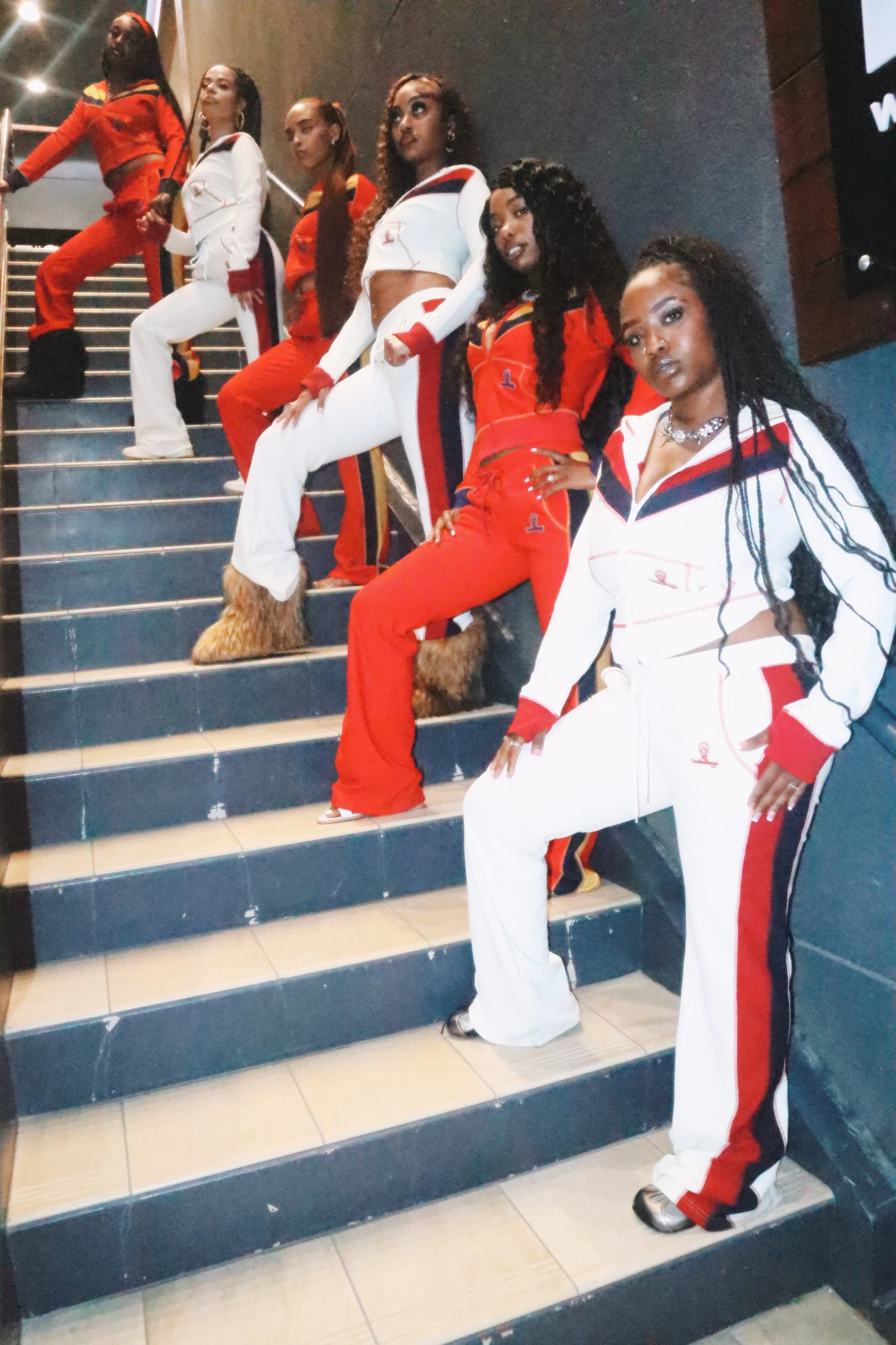 womens matching red and white jogging suits on a staircase inside a building.