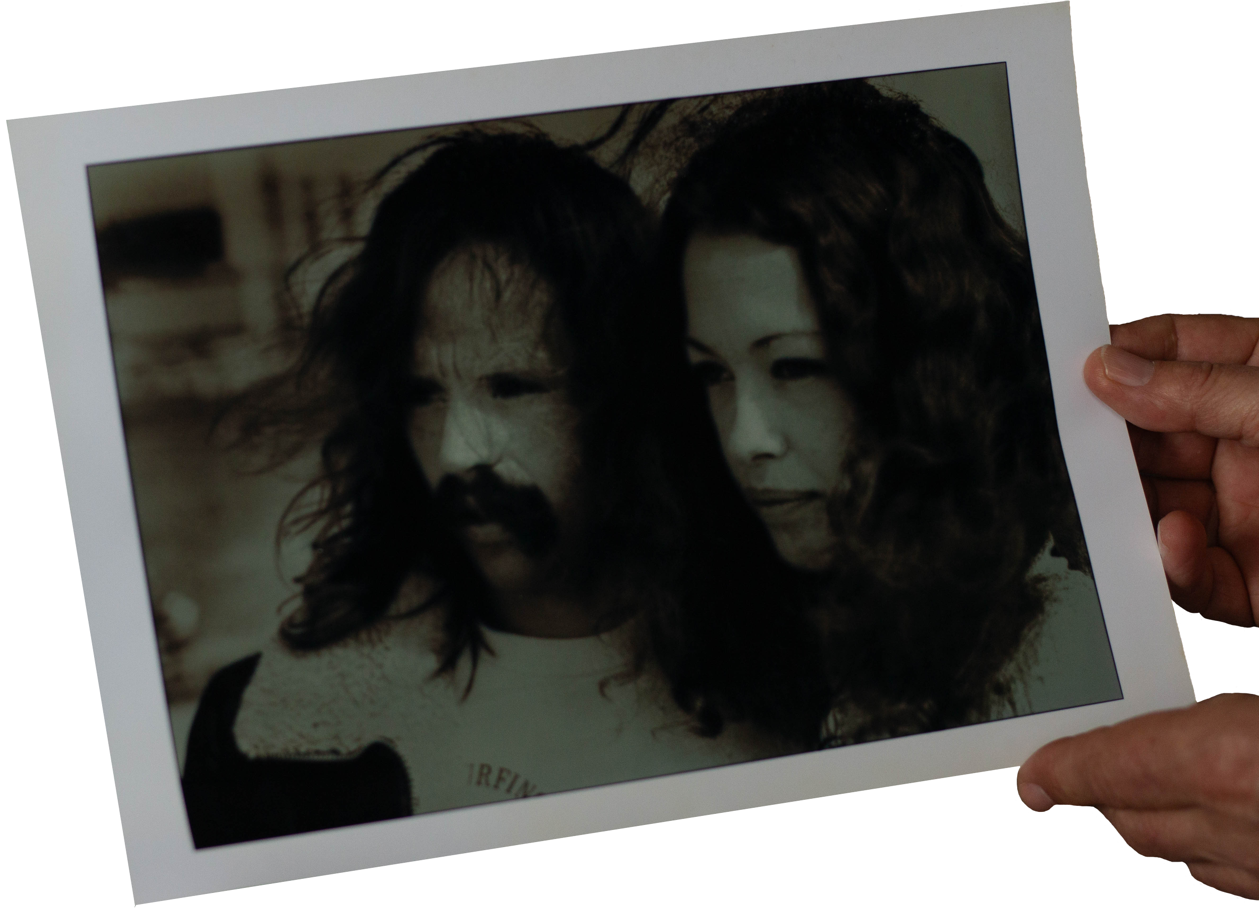 A black-and-white photograph of a man with long, wavy hair and a mustache and a woman with curly hair, both looking contemplative.