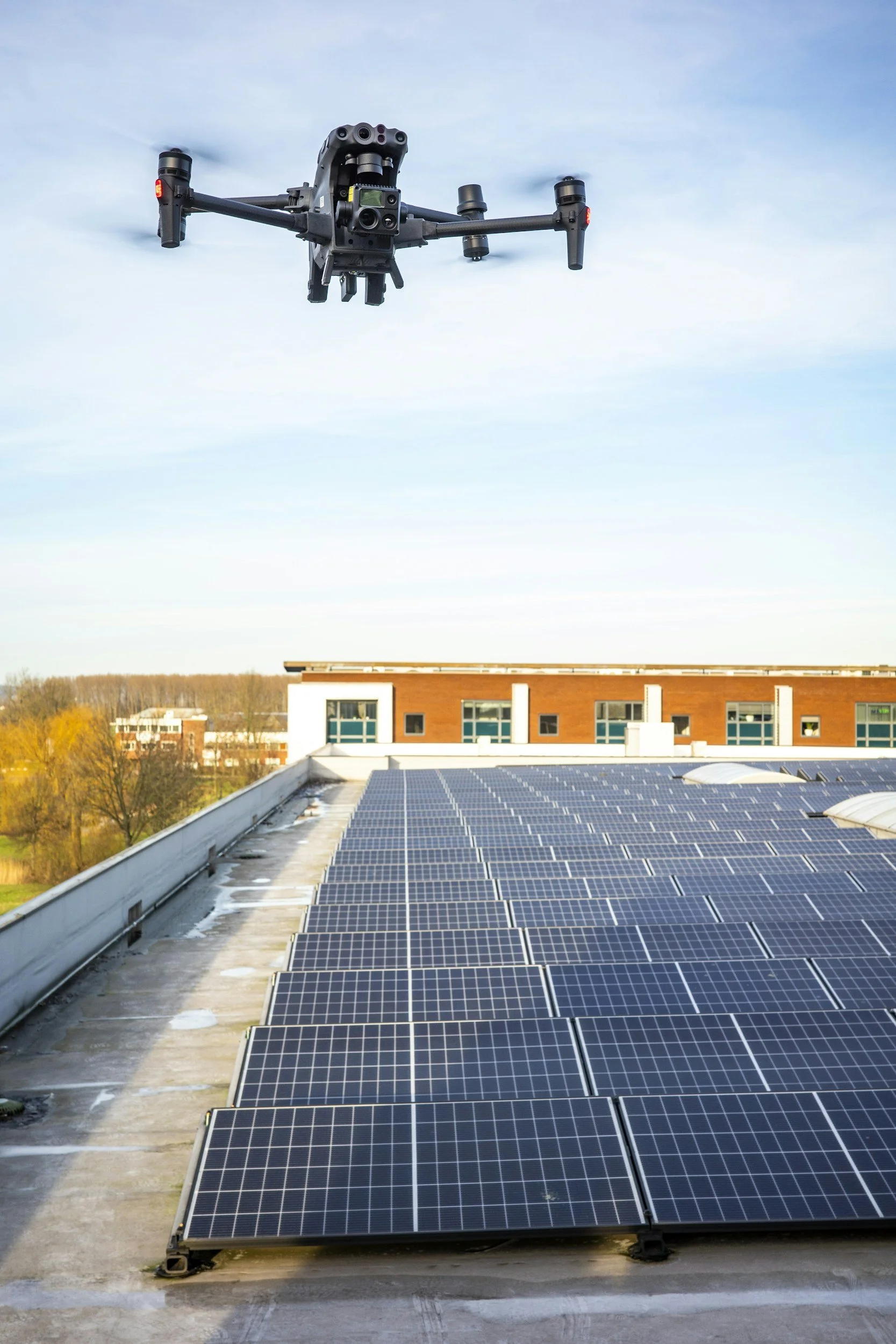 A drone flying above a building with solar panels on the roof.