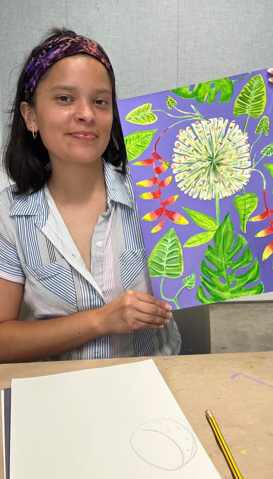 A student of Raphael Iaccarino's holding a vibrant painting of flowers and leaves.