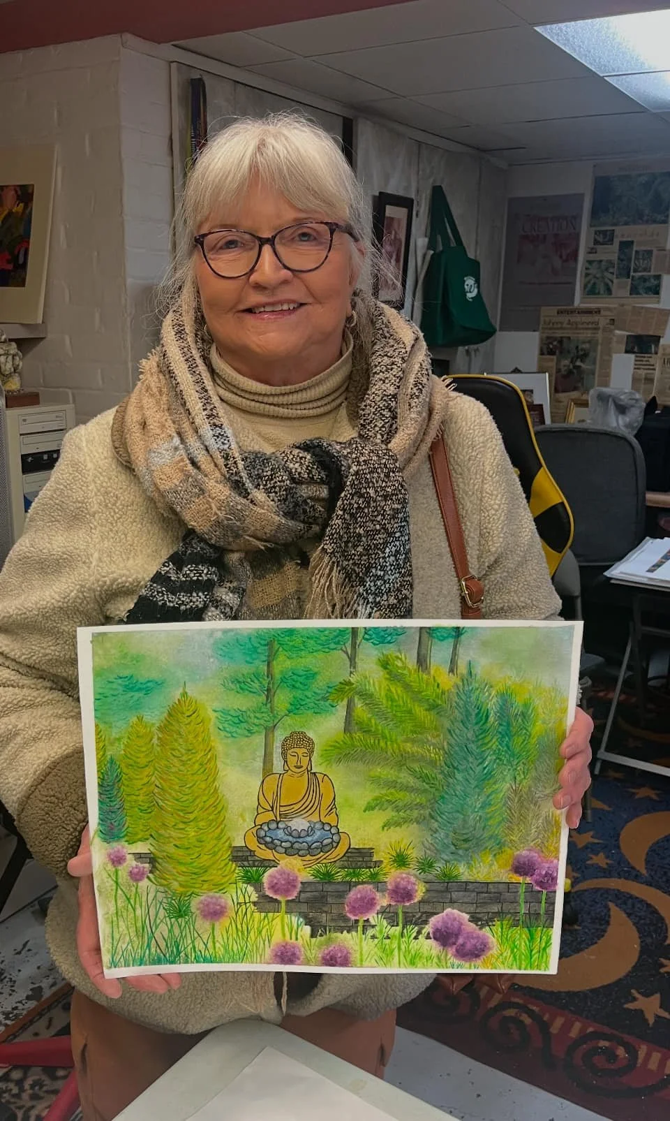 A student of Raphael Iaccarino's holding a colorful drawing of a garden with a Buddha statue.
