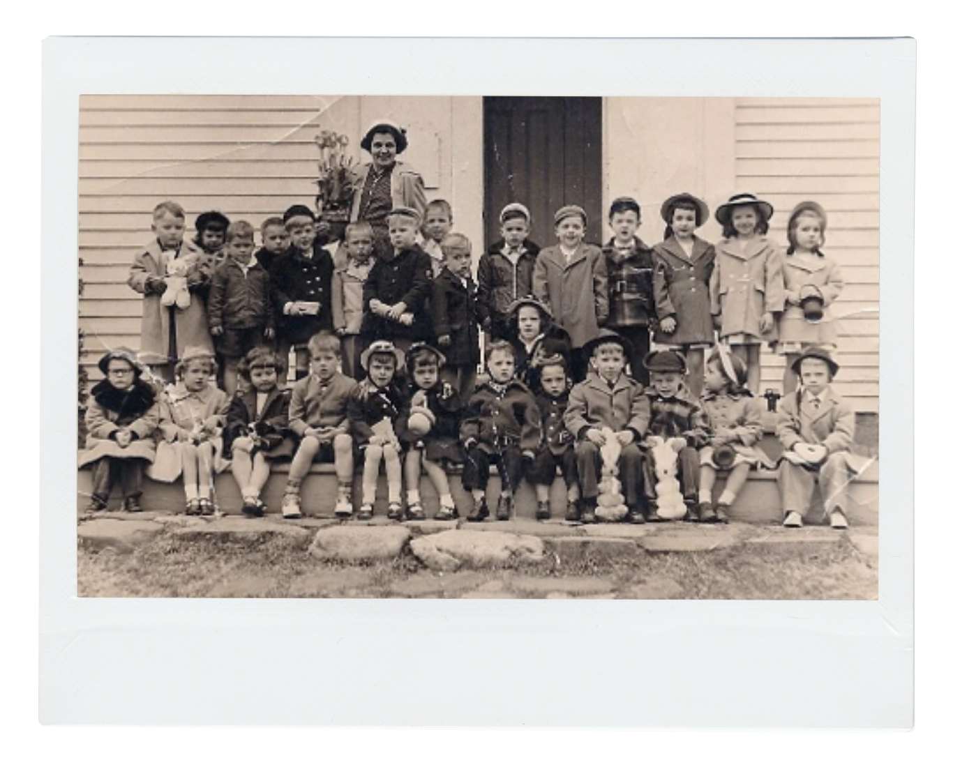 Modern house with wooden exterior in a mountainous landscape, with a large window showing two people inside.