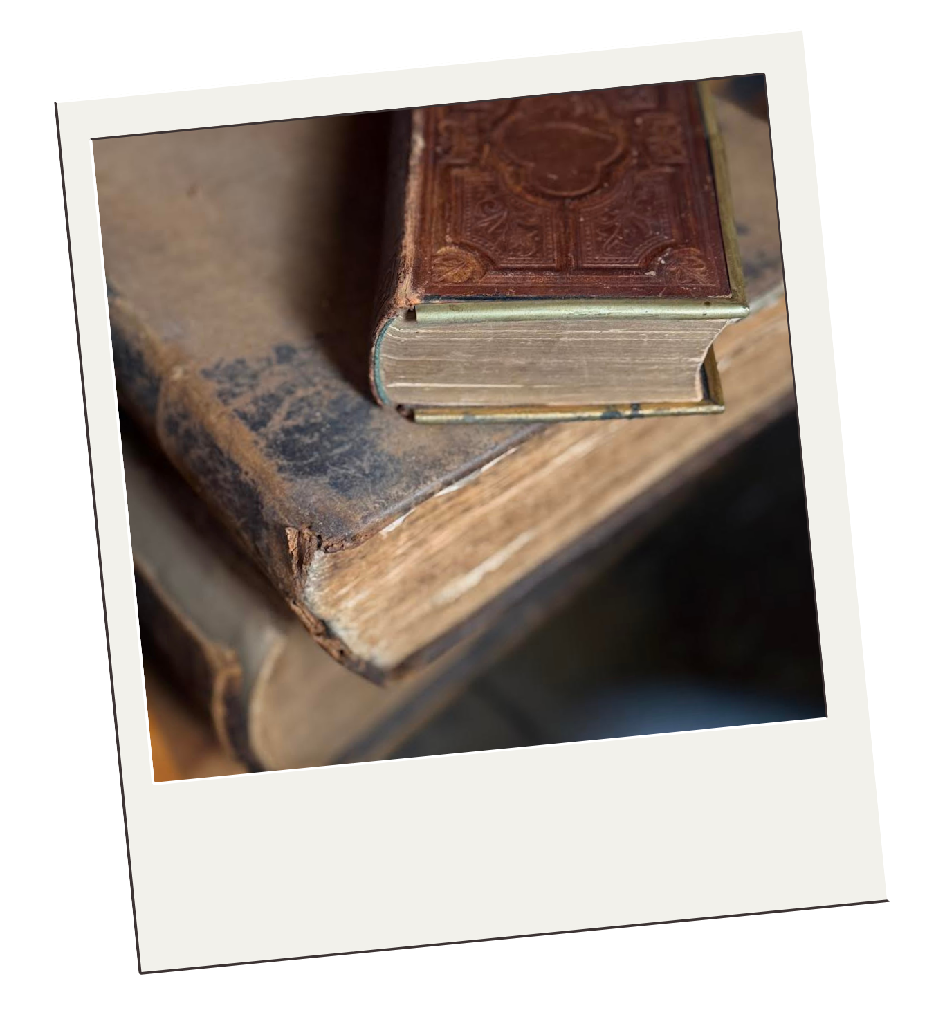 Close-up of two old, worn books with one older book underneath and a newer book on top, resting on a wooden surface.