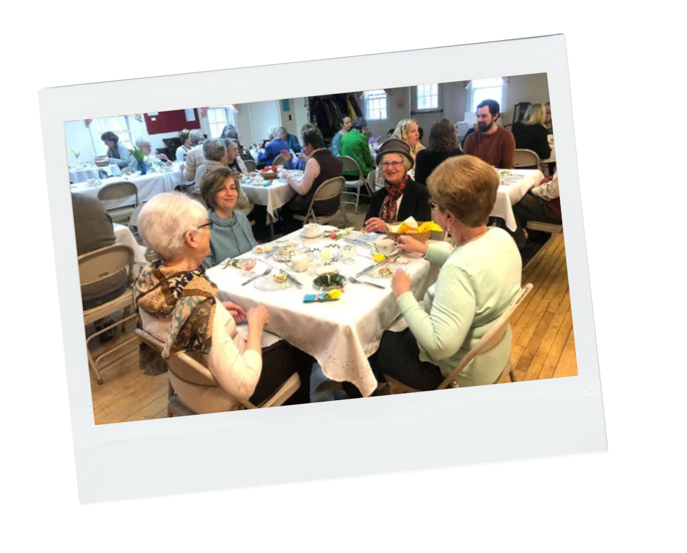 A landscape of mountains and a lake with green and brown rolling hills in the foreground, under a cloudy sky.