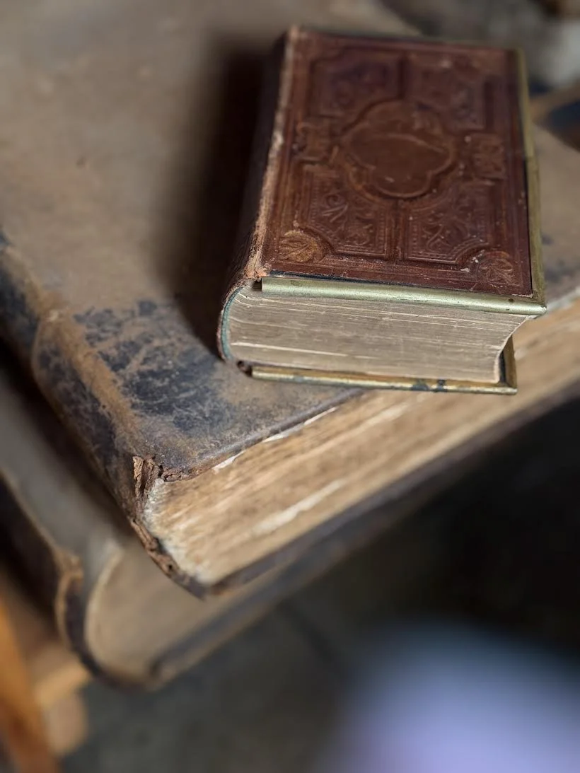 Close-up of an old, worn leather-bound book resting on a weathered wooden surface.