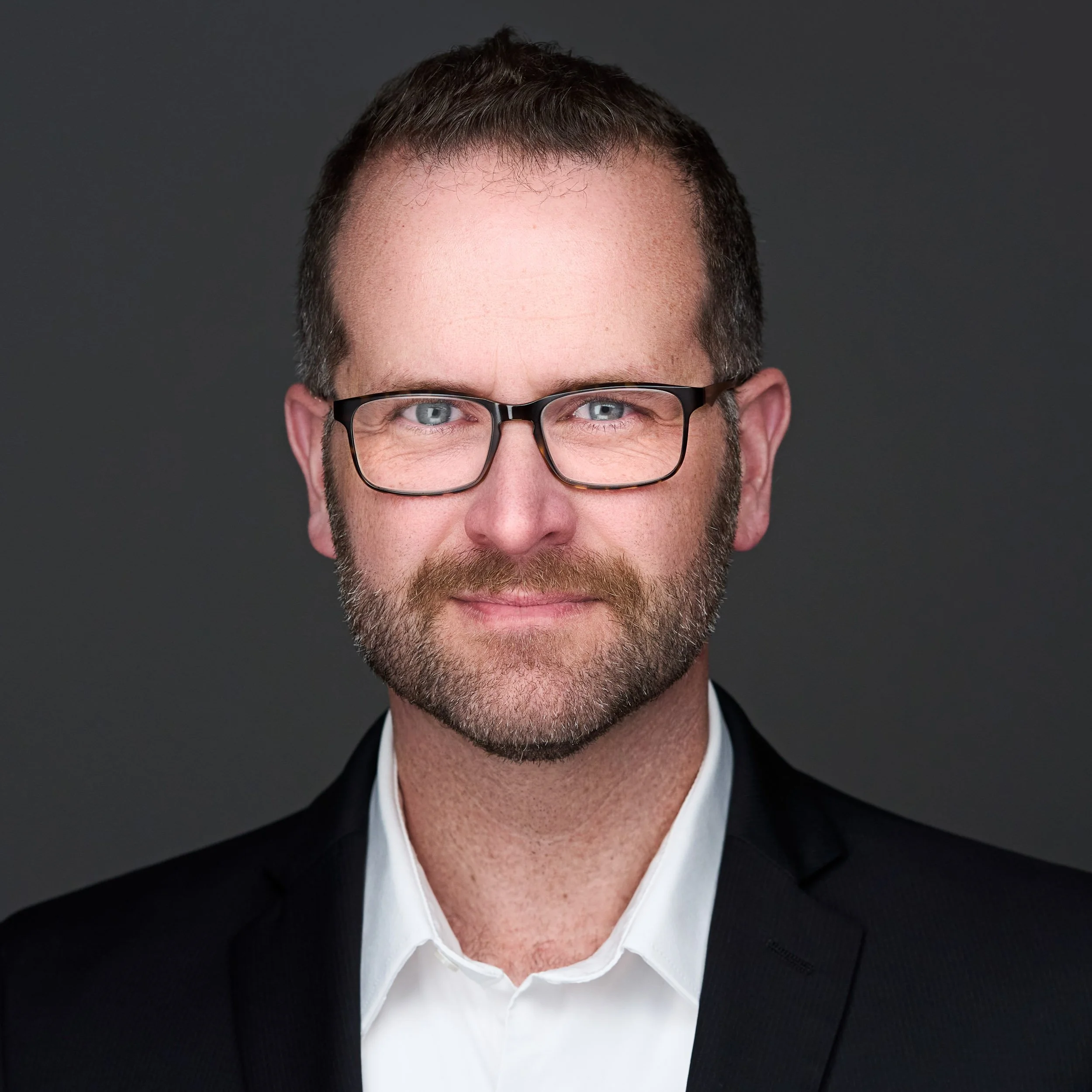 A construction worker wearing a yellow safety vest, helmet, and harness standing on a metal structure, working on a large white satellite dish or antenna.