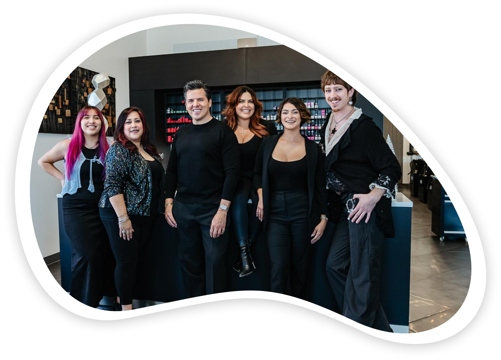Group of six people standing together inside a retail store, wearing black clothing, smiling at the camera.