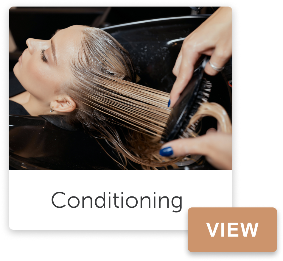 Woman getting her hair conditioned at a salon, lying with her eyes closed while a stylist applies conditioner to her wet hair.