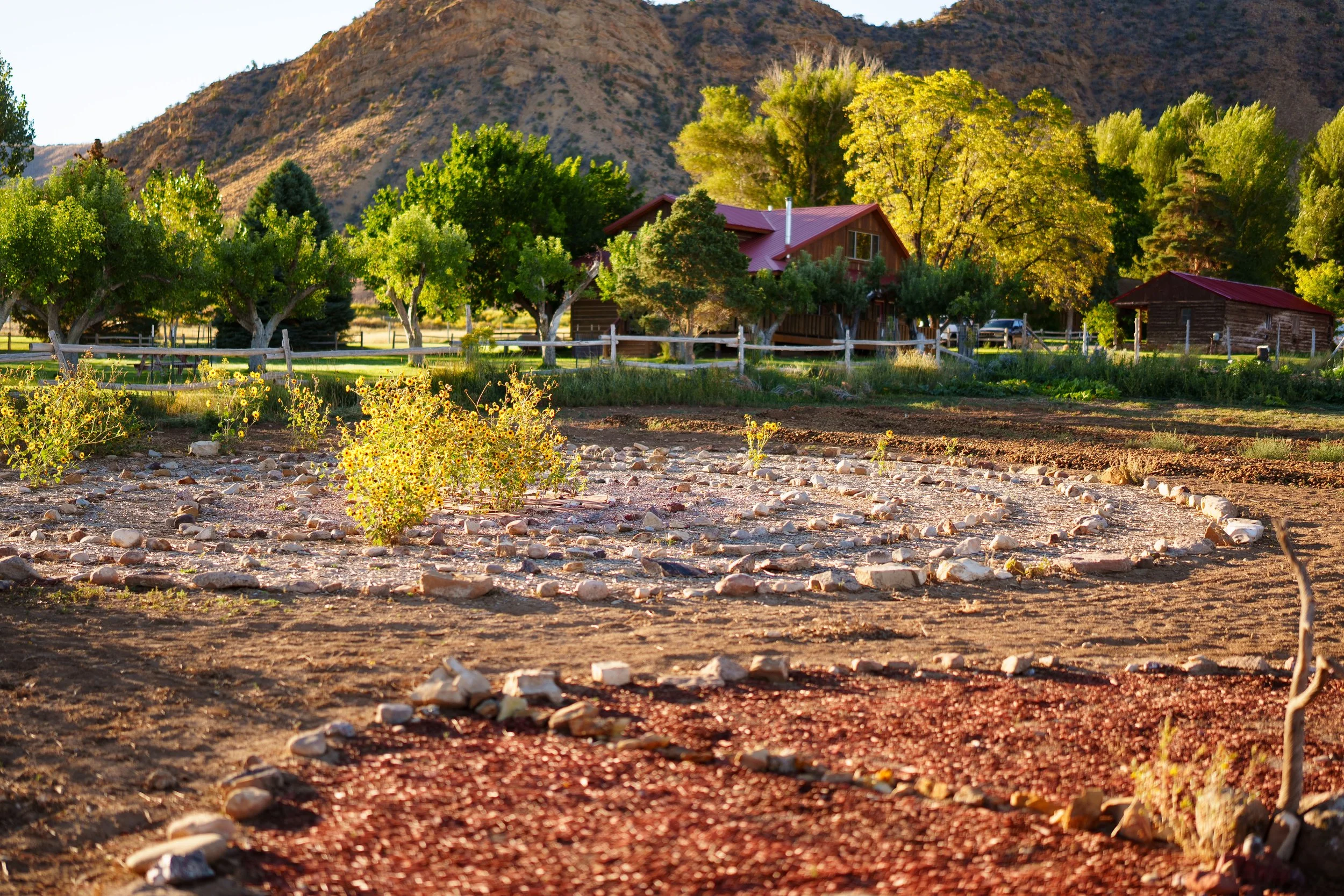 Rustic rental cabin in Moab Utah with outdoor barbeque patio, rich foliage, and shady trees.