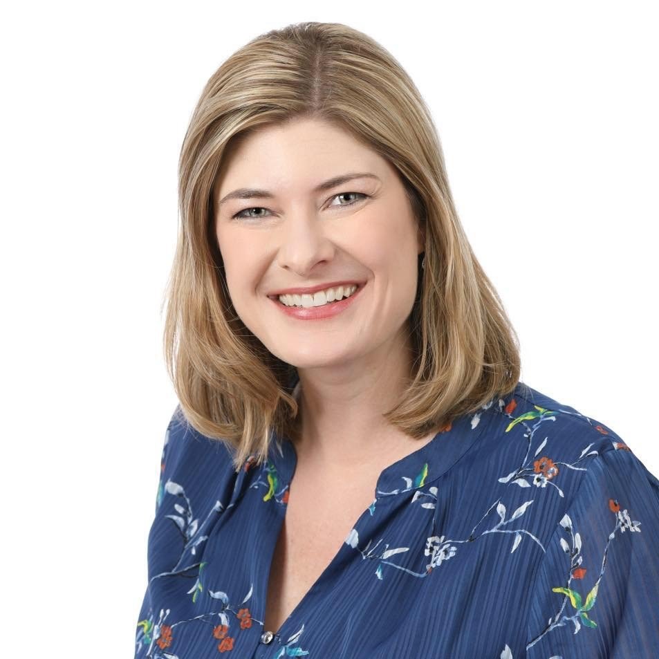 Headshot of a woman with shoulder-length blonde hair, smiling, wearing a blue floral blouse.