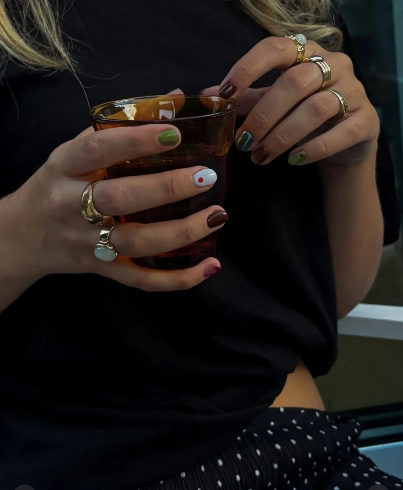 Creative nail art manicure with rings holding a drink at a private event