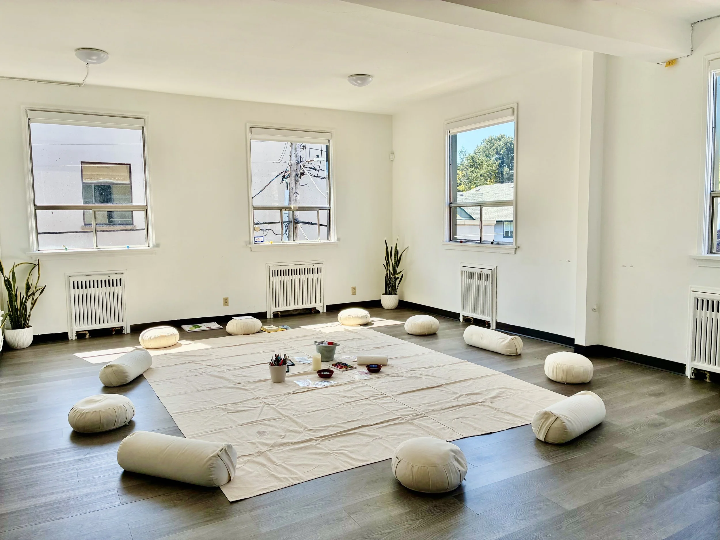Bright, empty studio with floor cushions arranged in a circle around a drop cloth