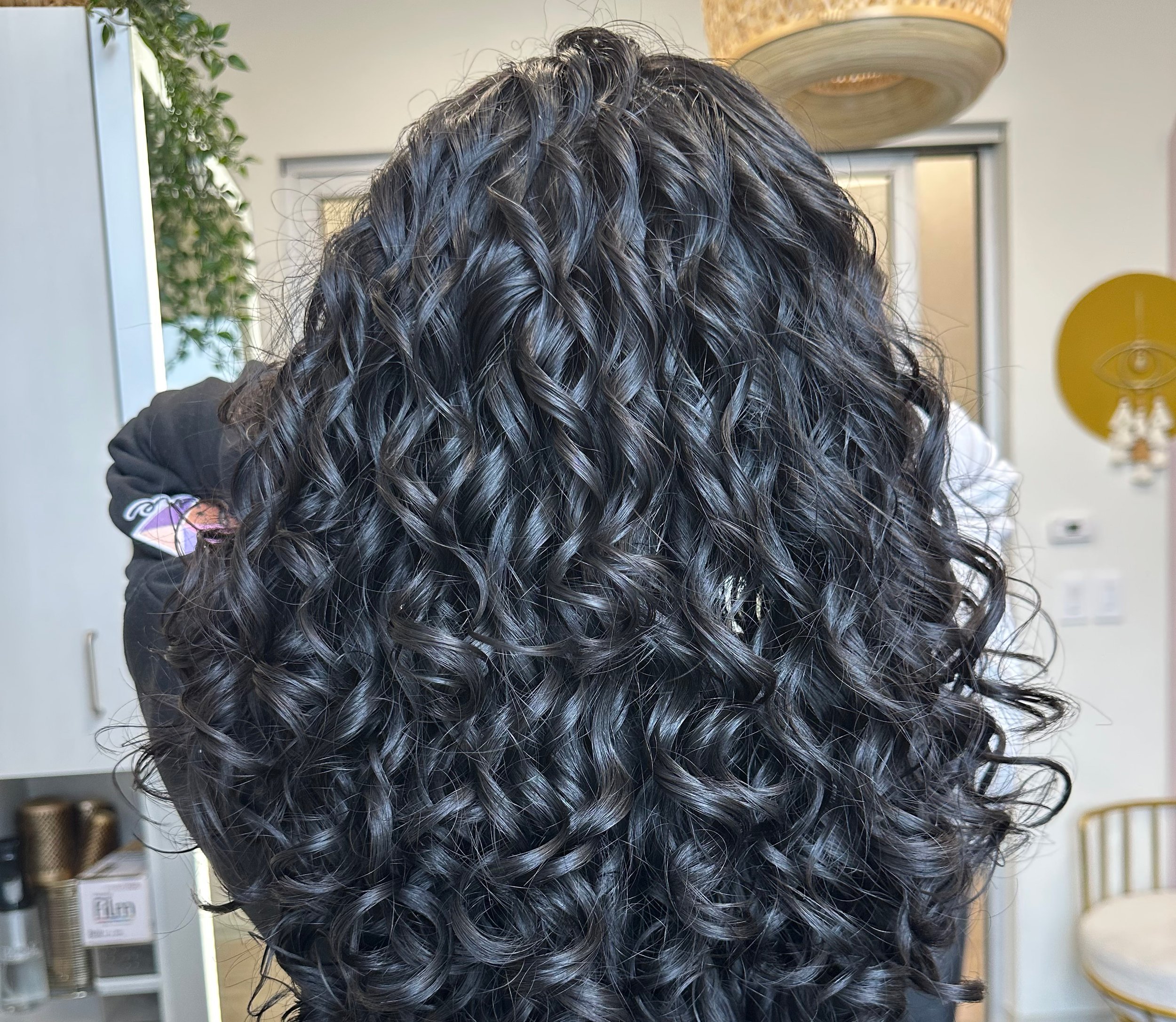 A close-up photo of dark all over color on a curly client.