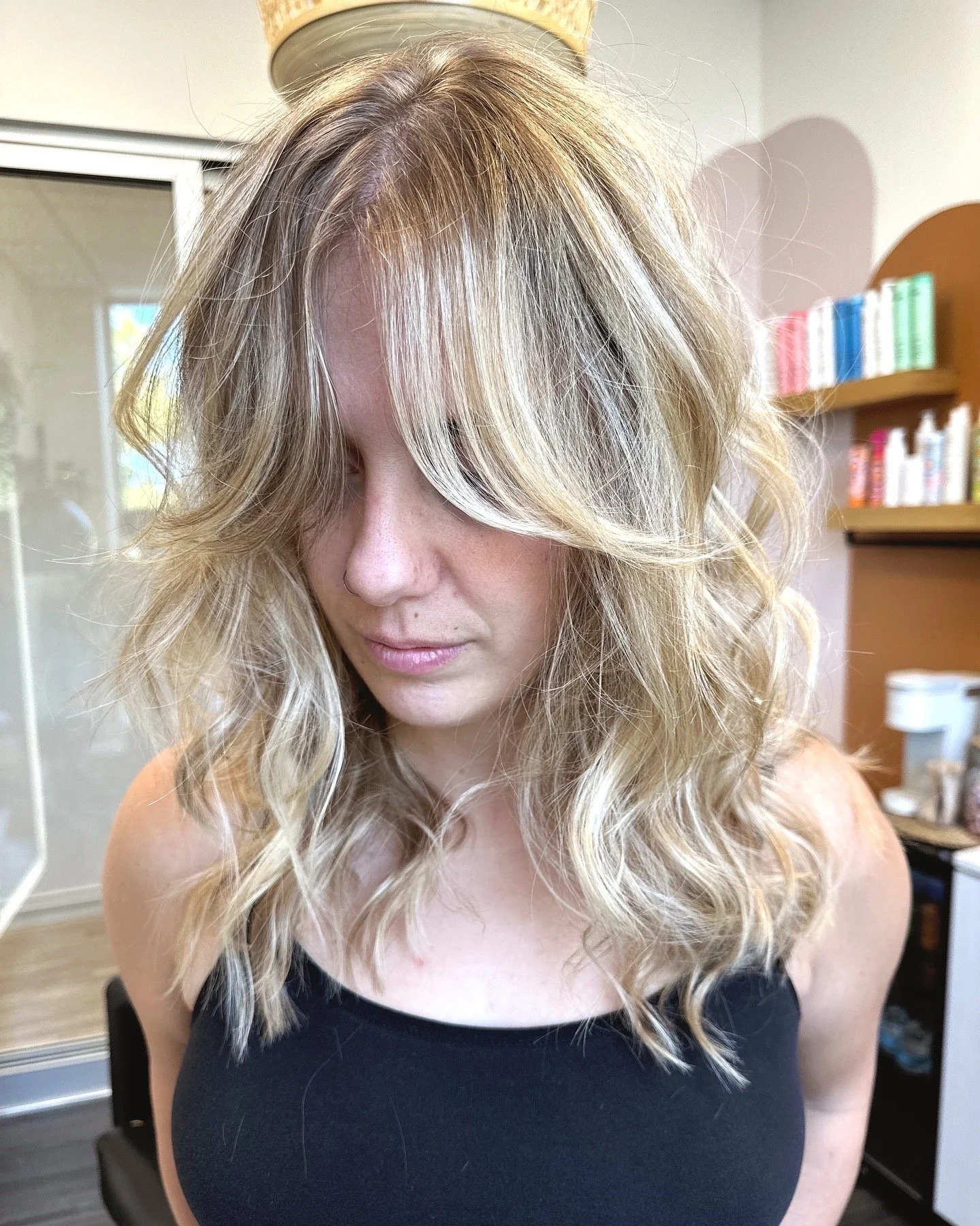 Photo of a client with long blond hair featuring balayage and soft curtain bangs. 