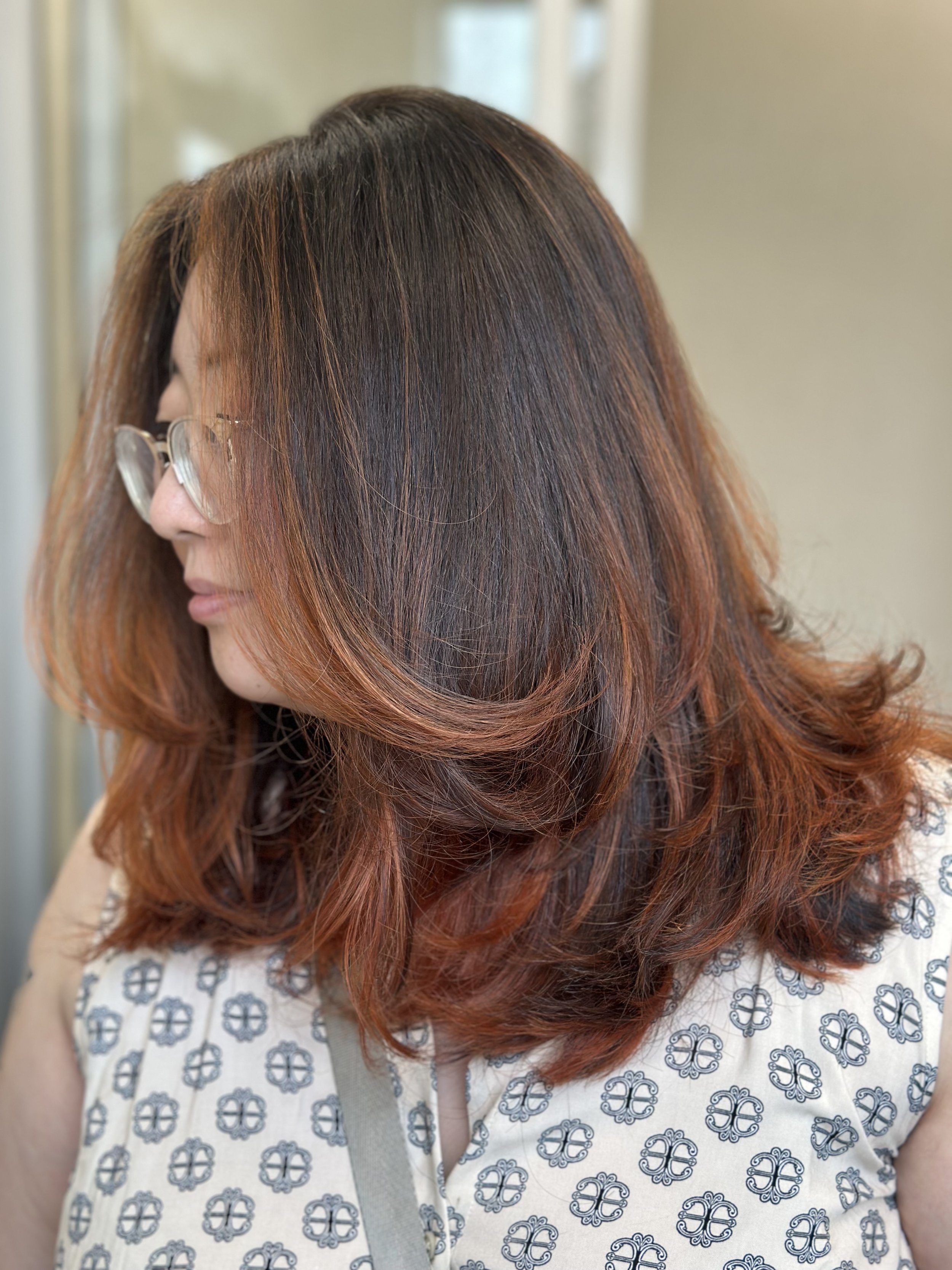 Photo of a client with long dark hair featuring face-framing red highlights.
