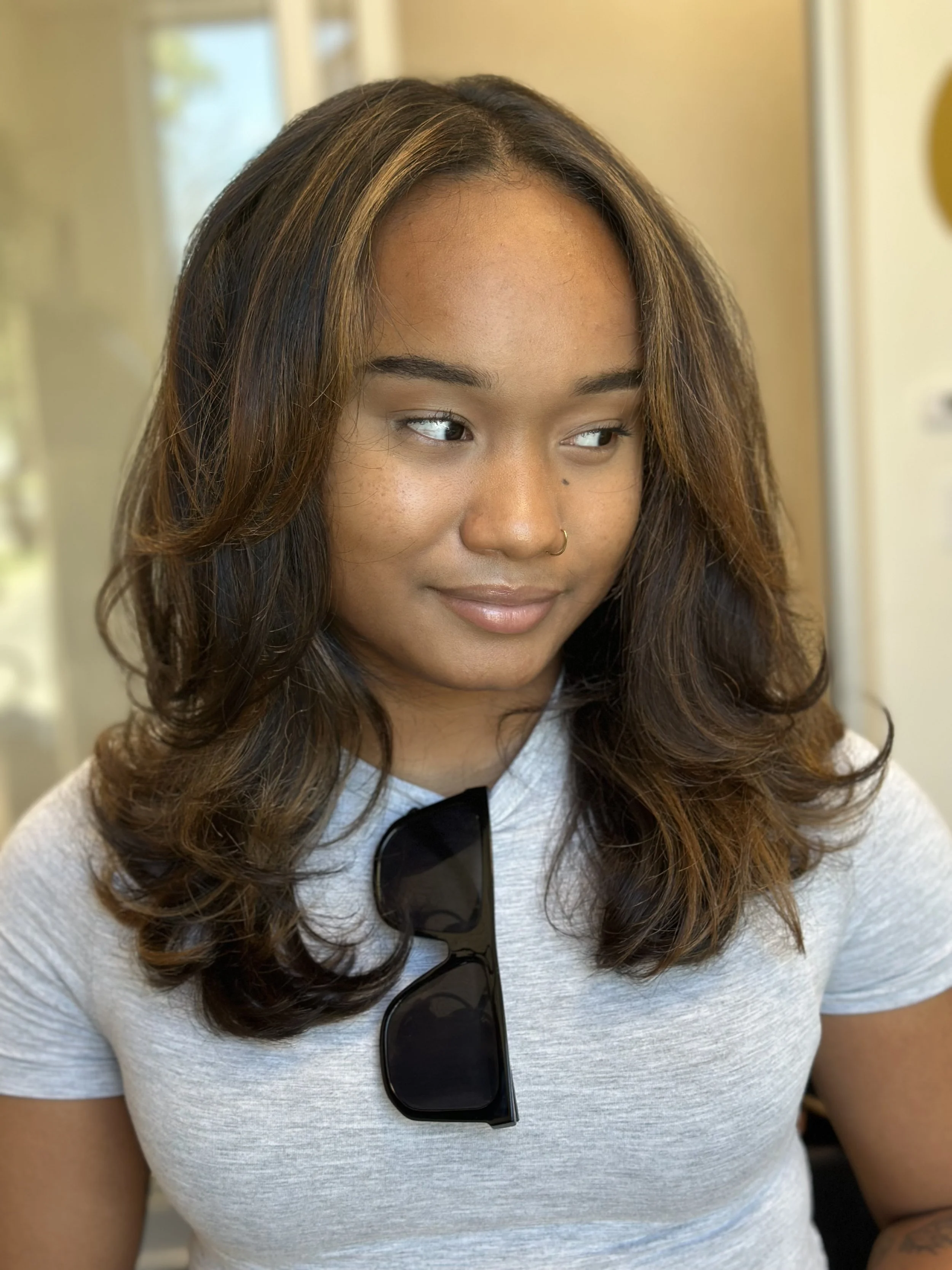 Photo of a client with long, curtain bangs and face-framing highlights.