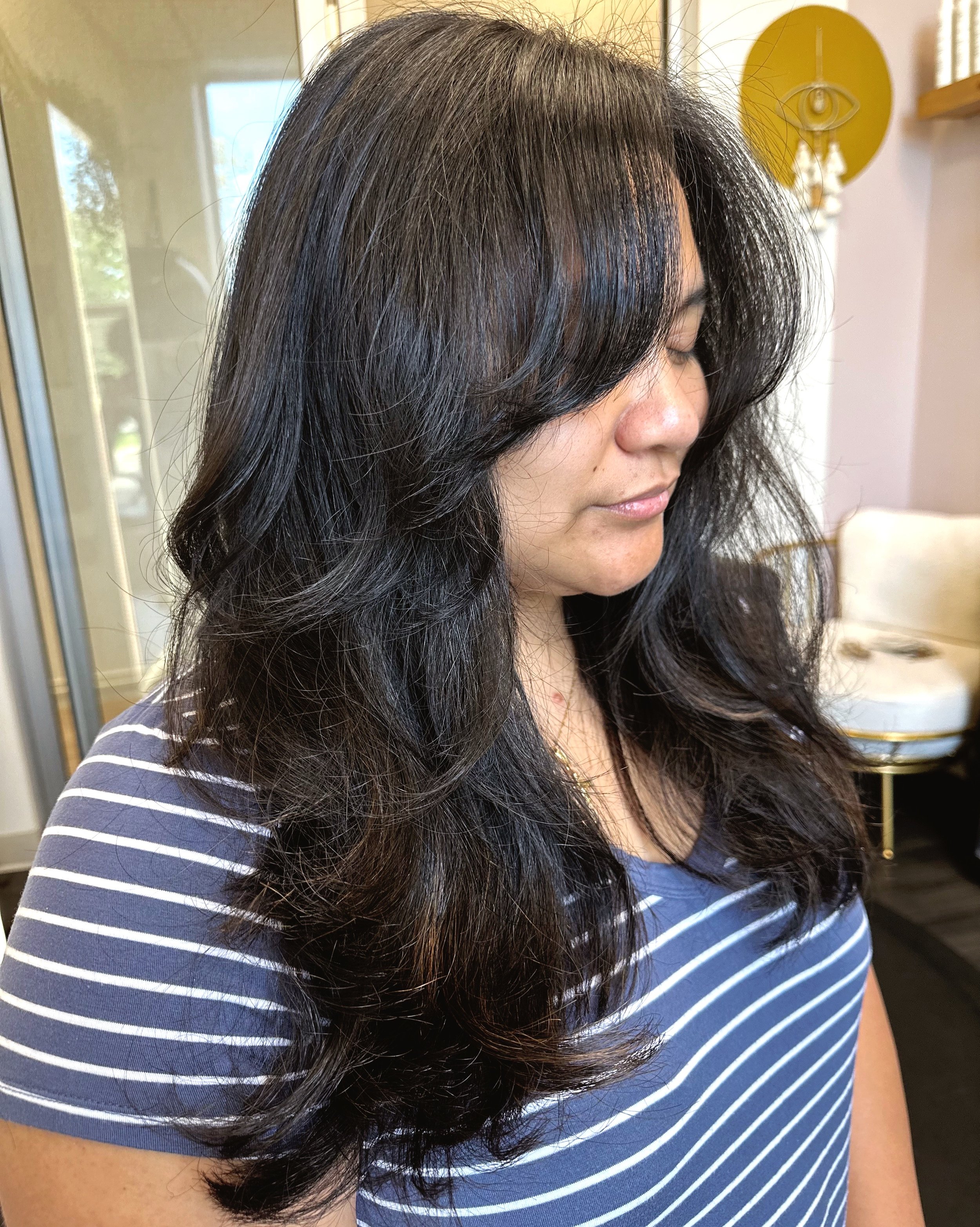 Photo of a client with long dark hair, curtain bangs, and soft waves.