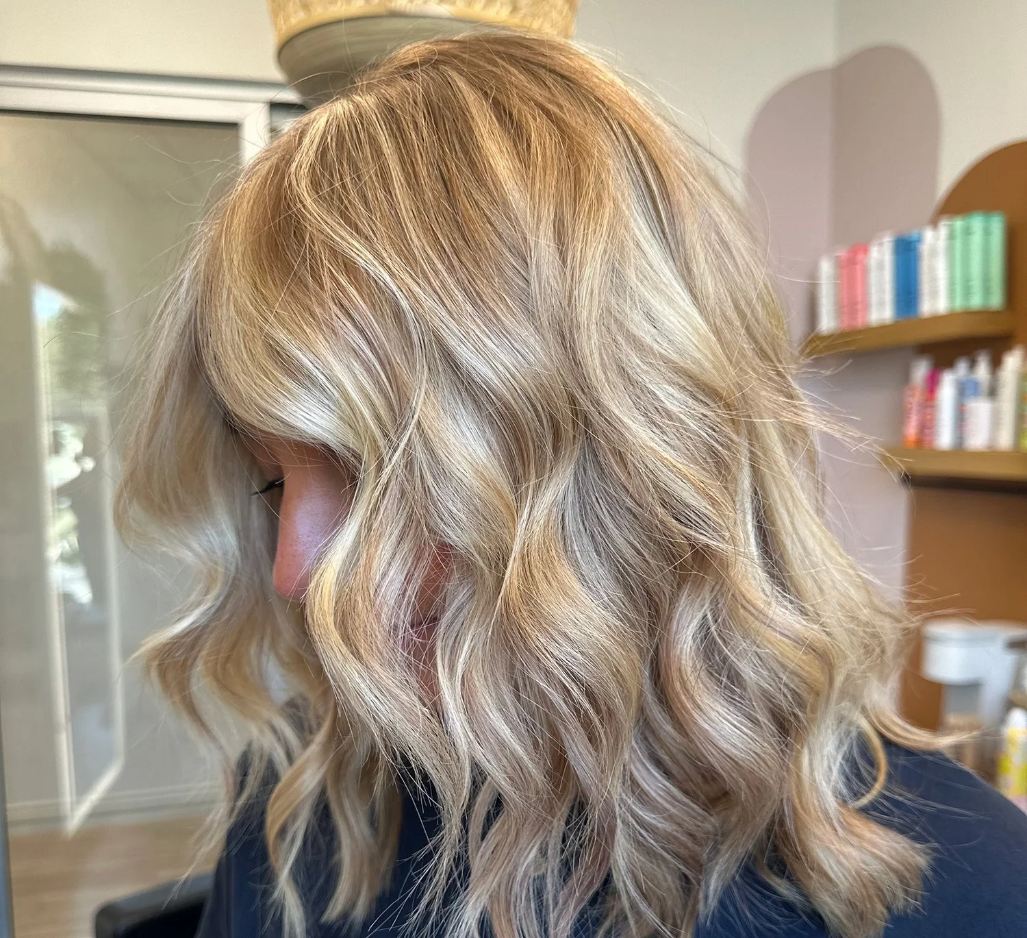 A photo of a client with vibrant blond hair with lots of dimension.