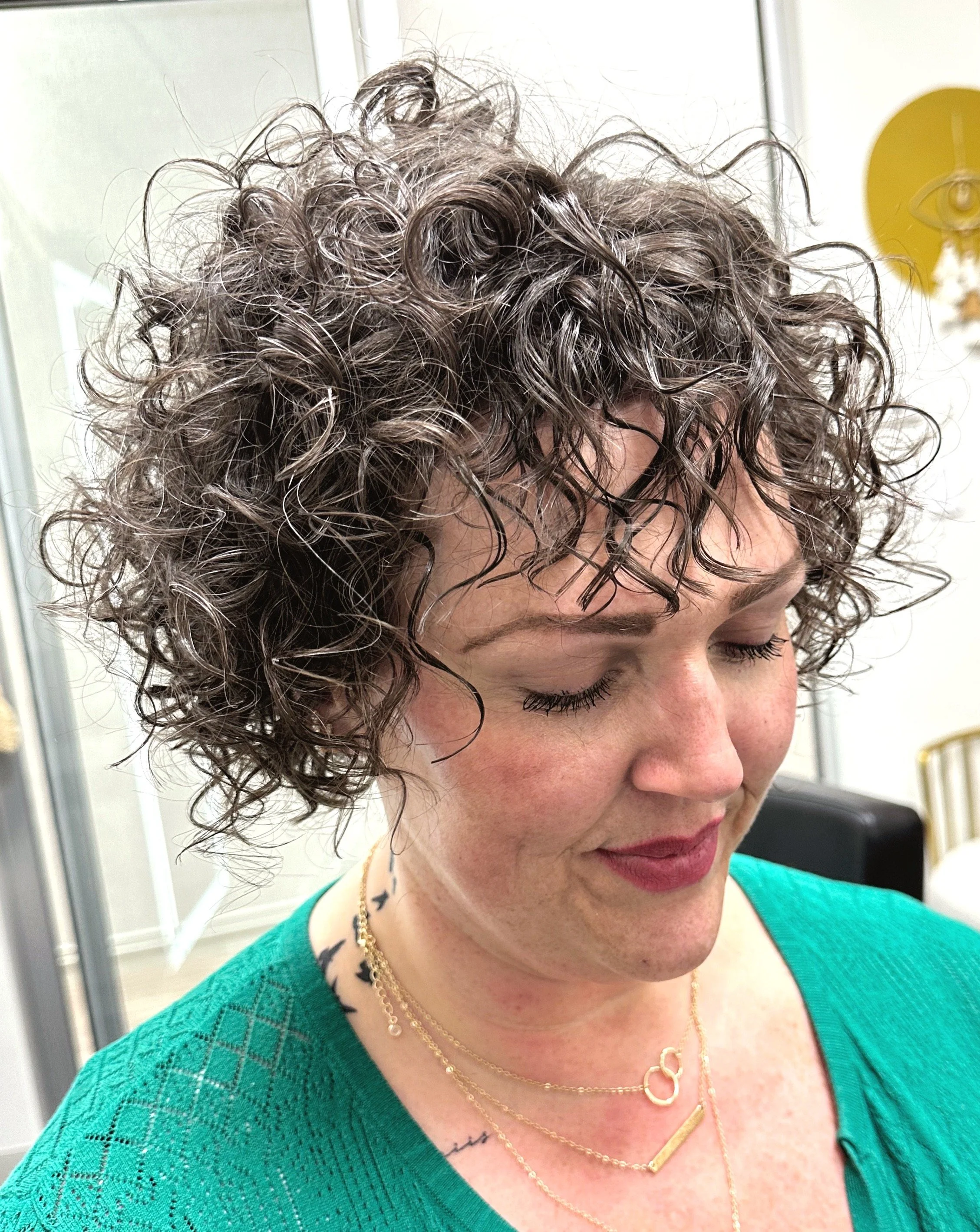 Photo of a client rocking a curly bob-style haircut with lots of volume. 