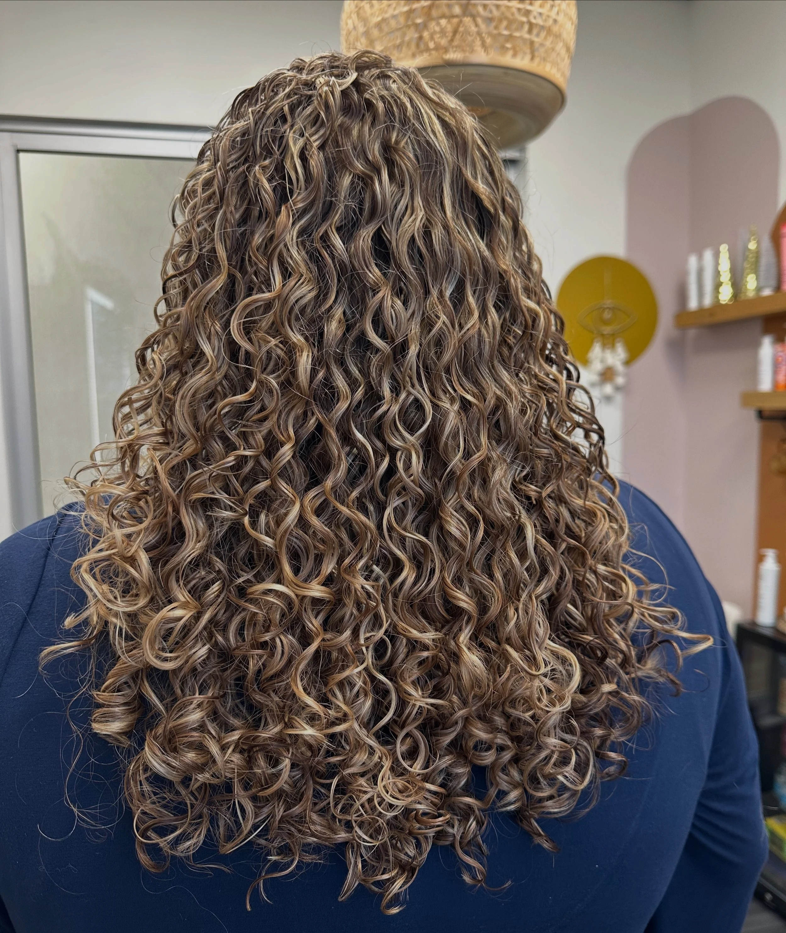 Photo of a client facing away from the camera, with long curly hair.
