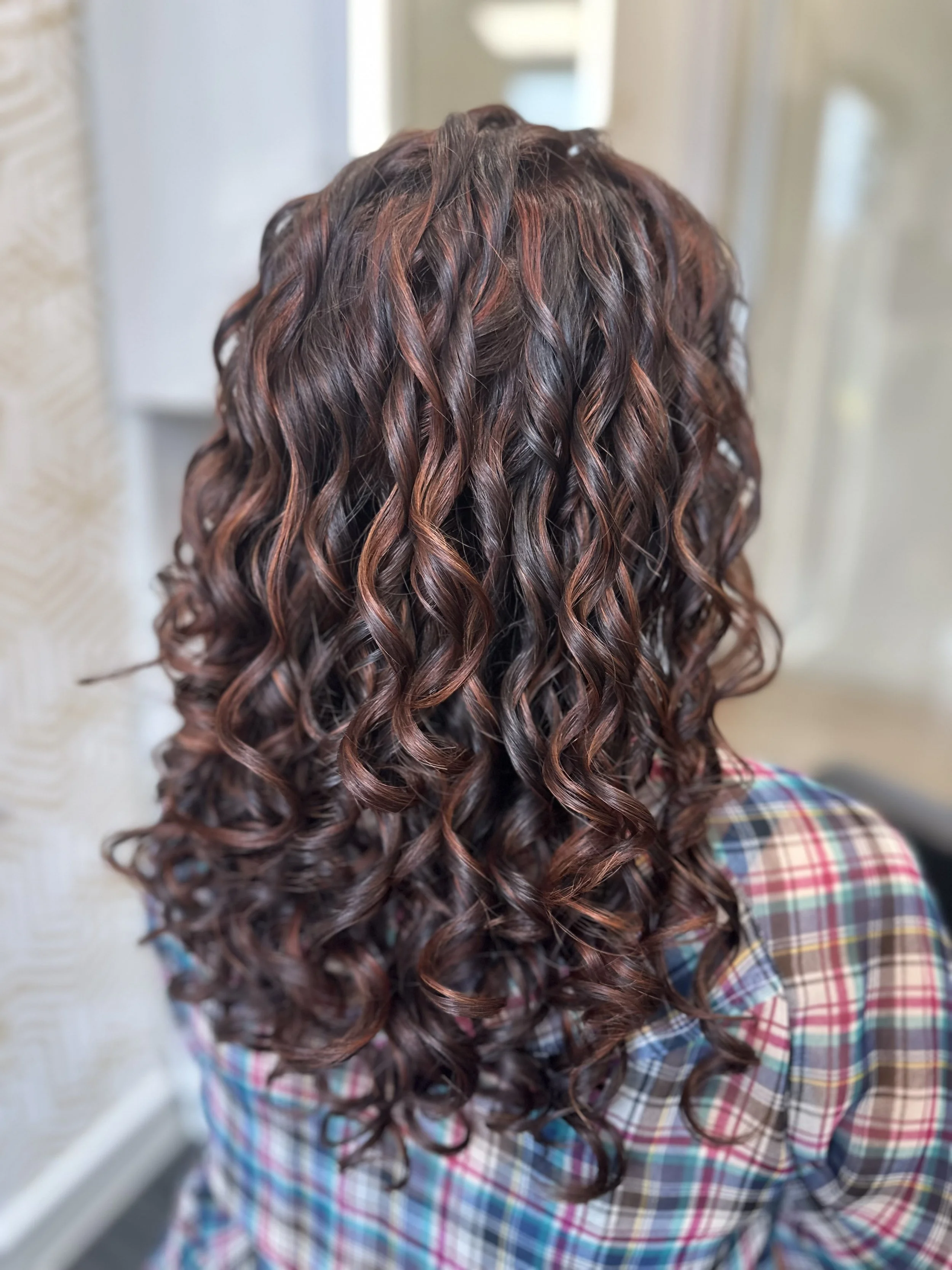 Photo of a client with long curls, showing strong dimension. 