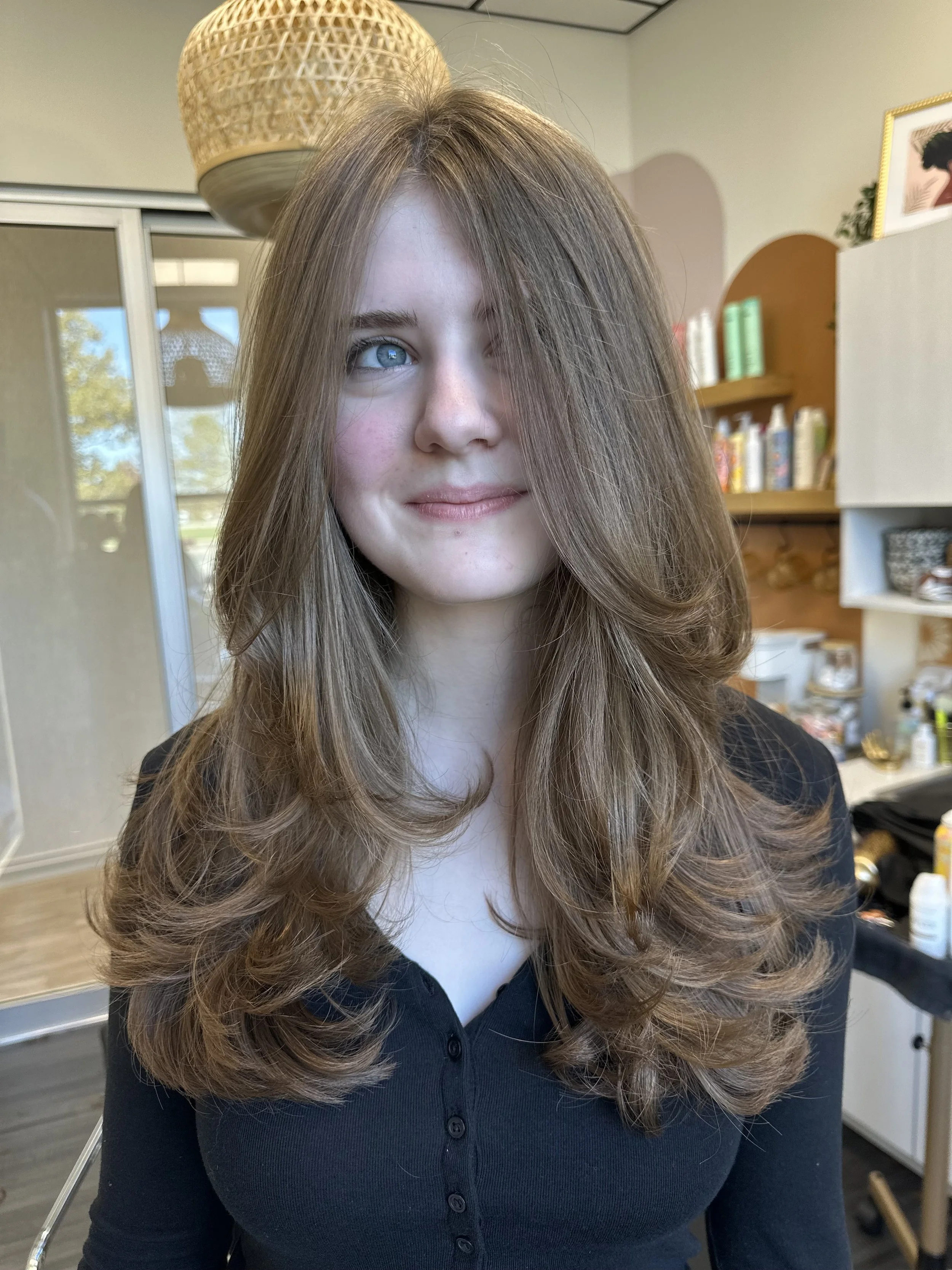Photo of a client with very long brown hair with lots of layers and wavy face framing.