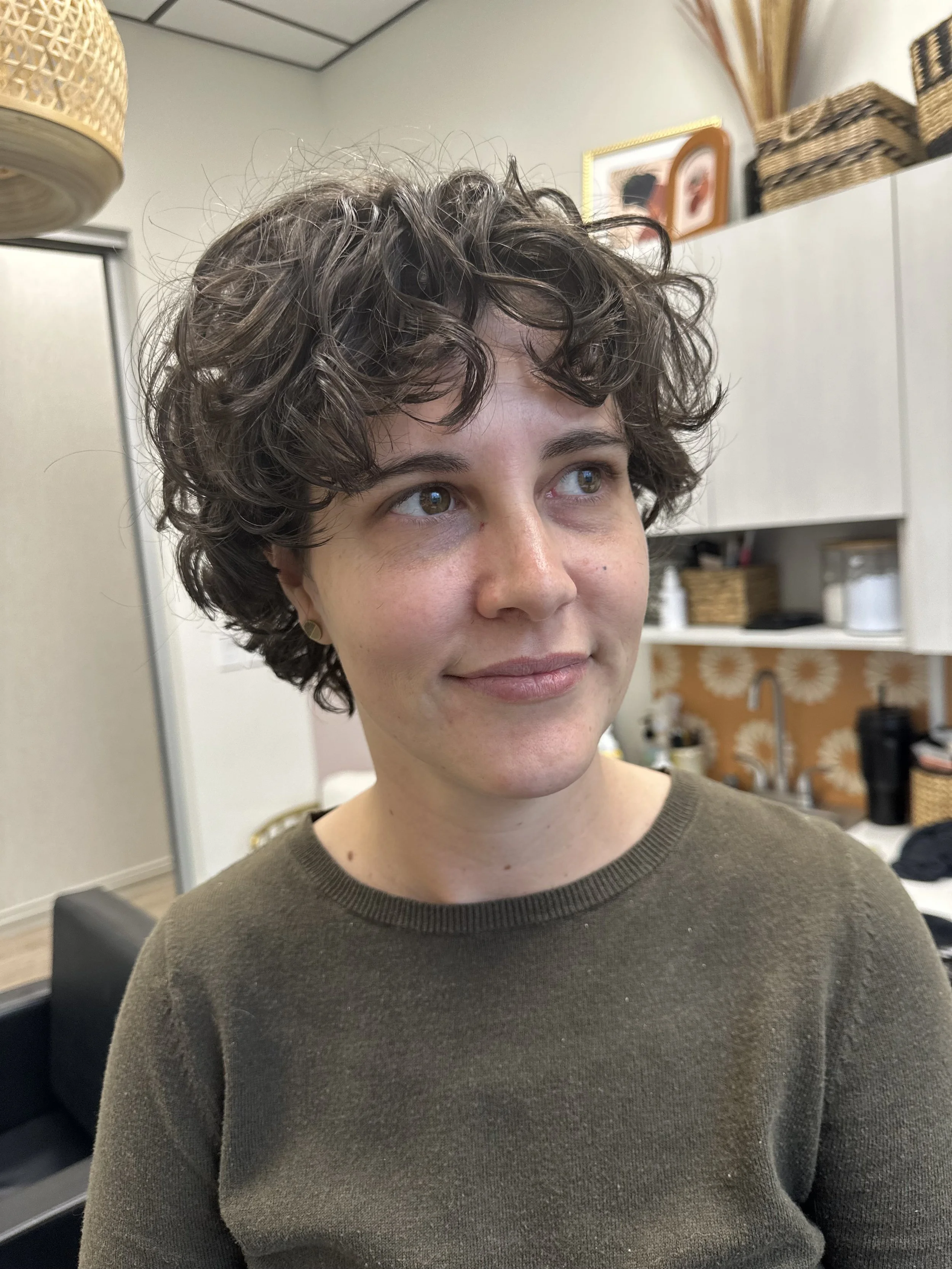 Photo of a client with short, dark curly hair.