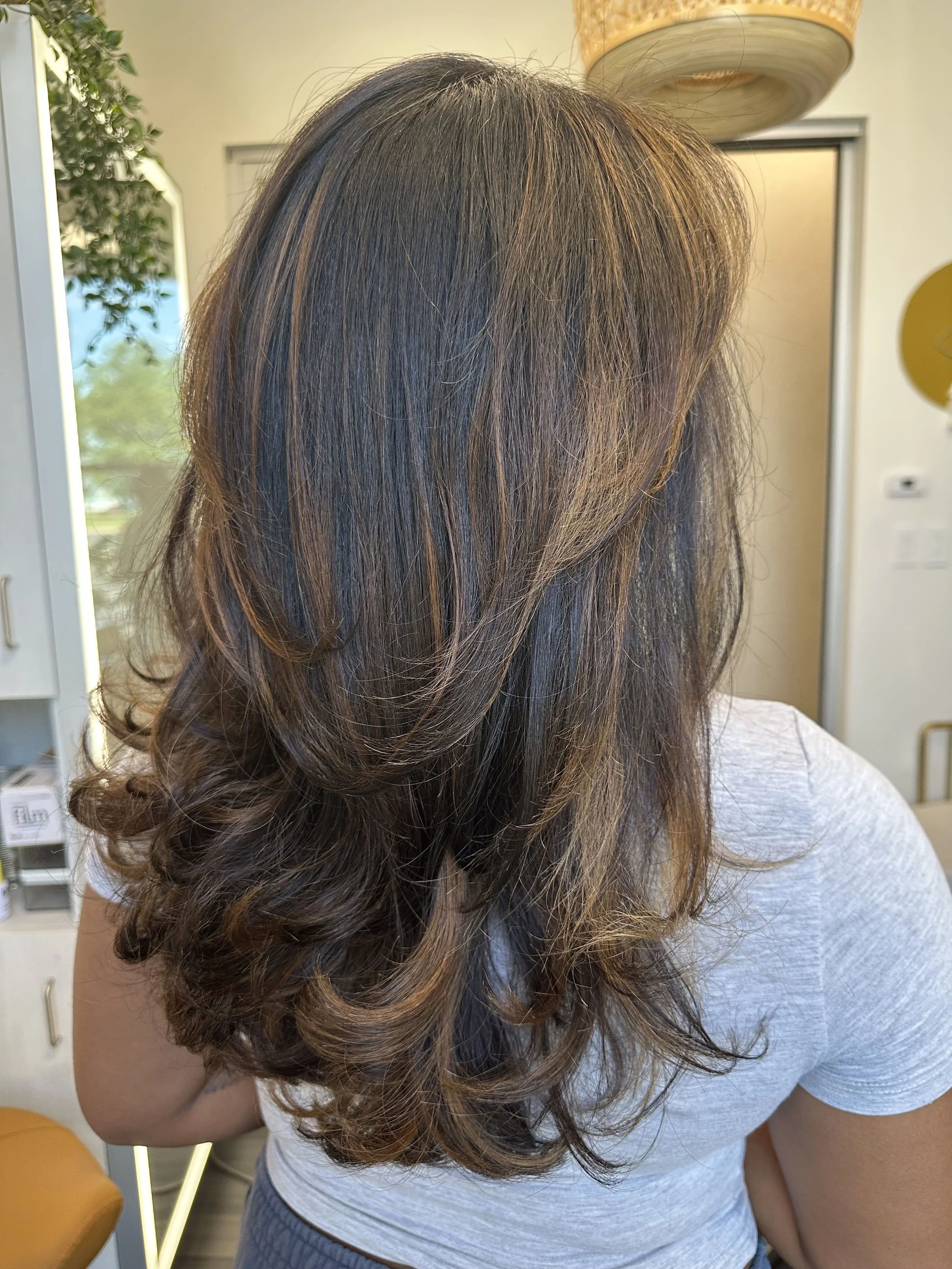 Photo of a client with long hair showing reddish highlights and strong dimension. 