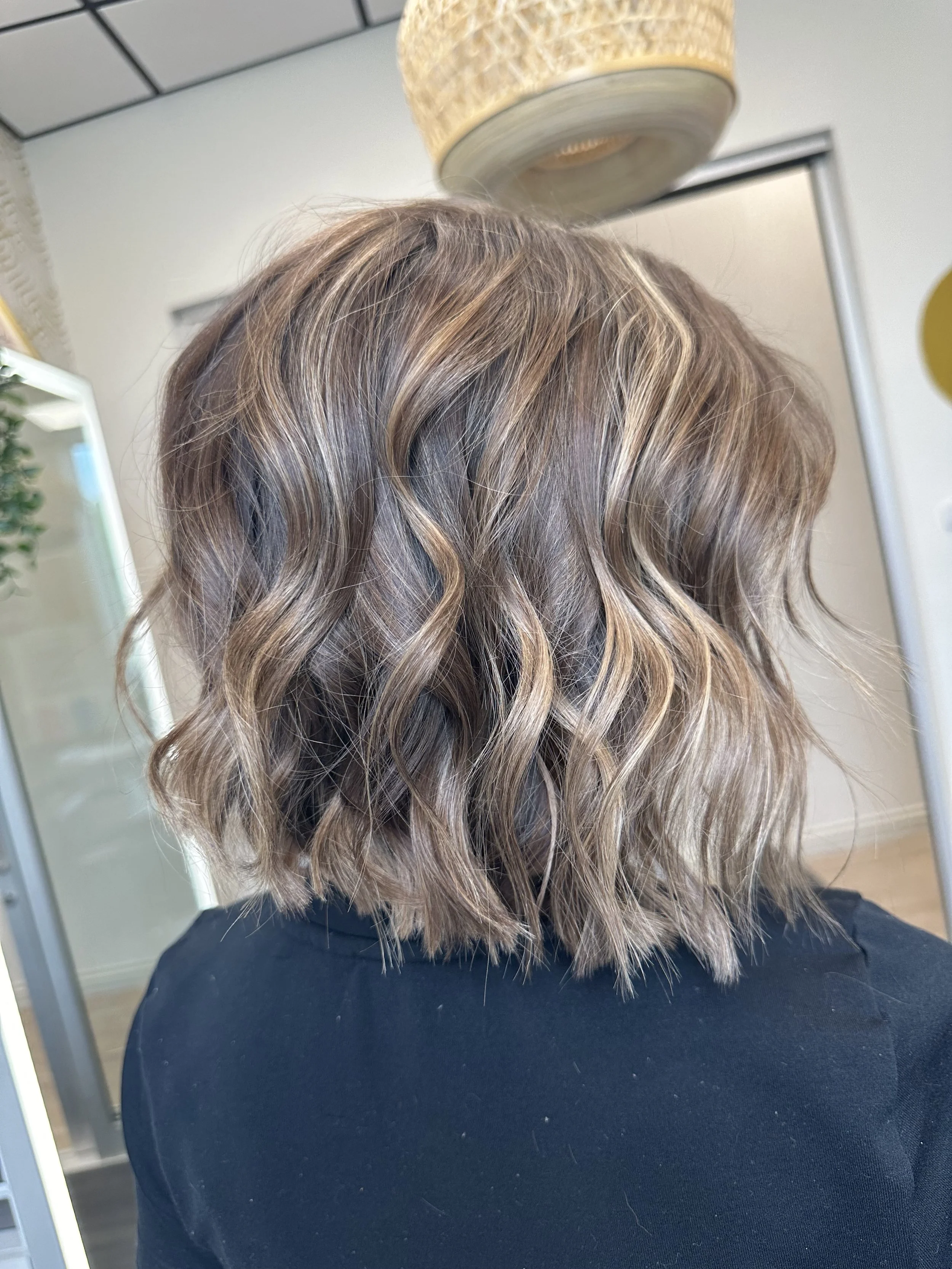 Photo of a client rocking a bob style cut with lots of blonde highlights and dimension. 