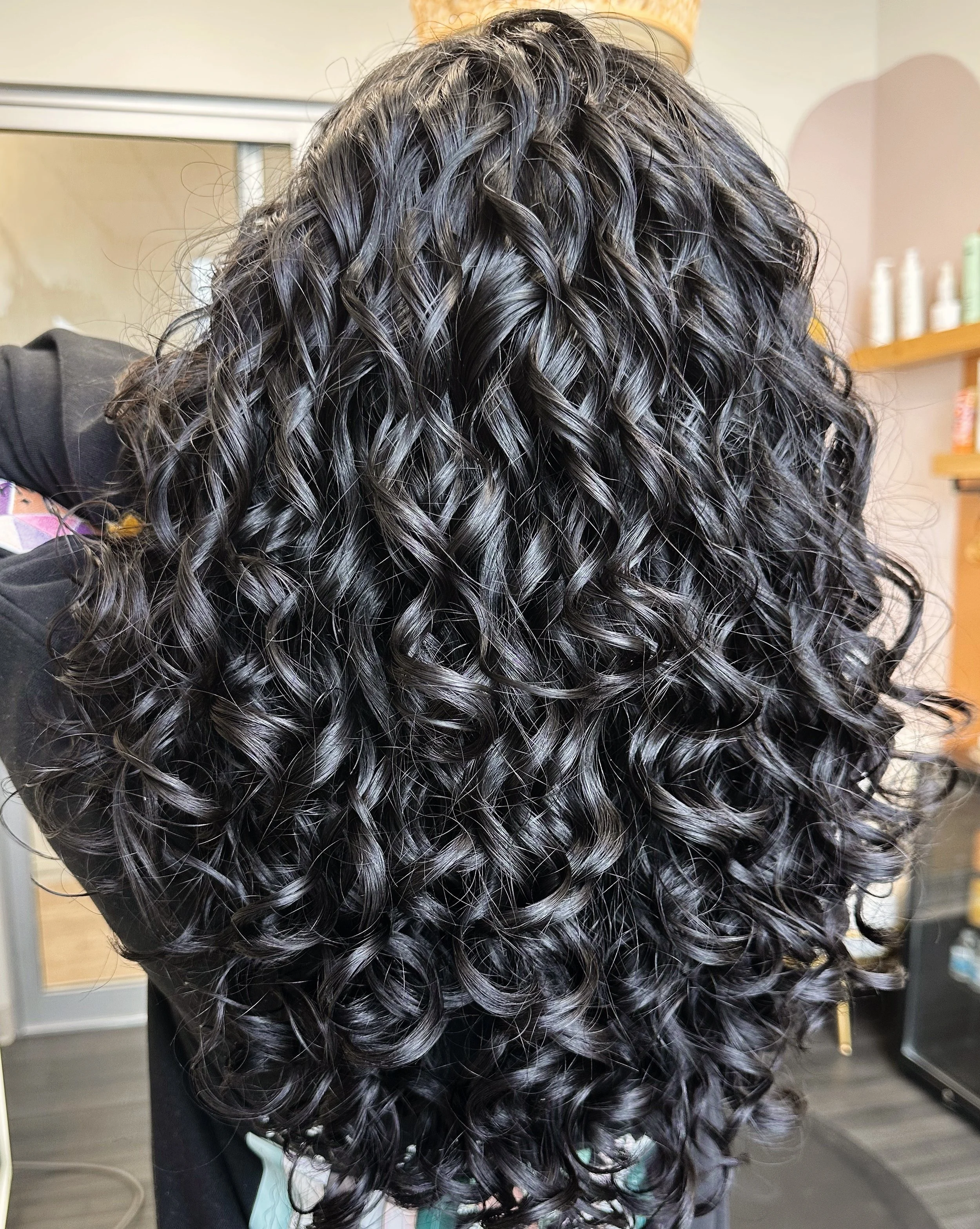 Photo of a client with very dark, thick curls cascading down her back.