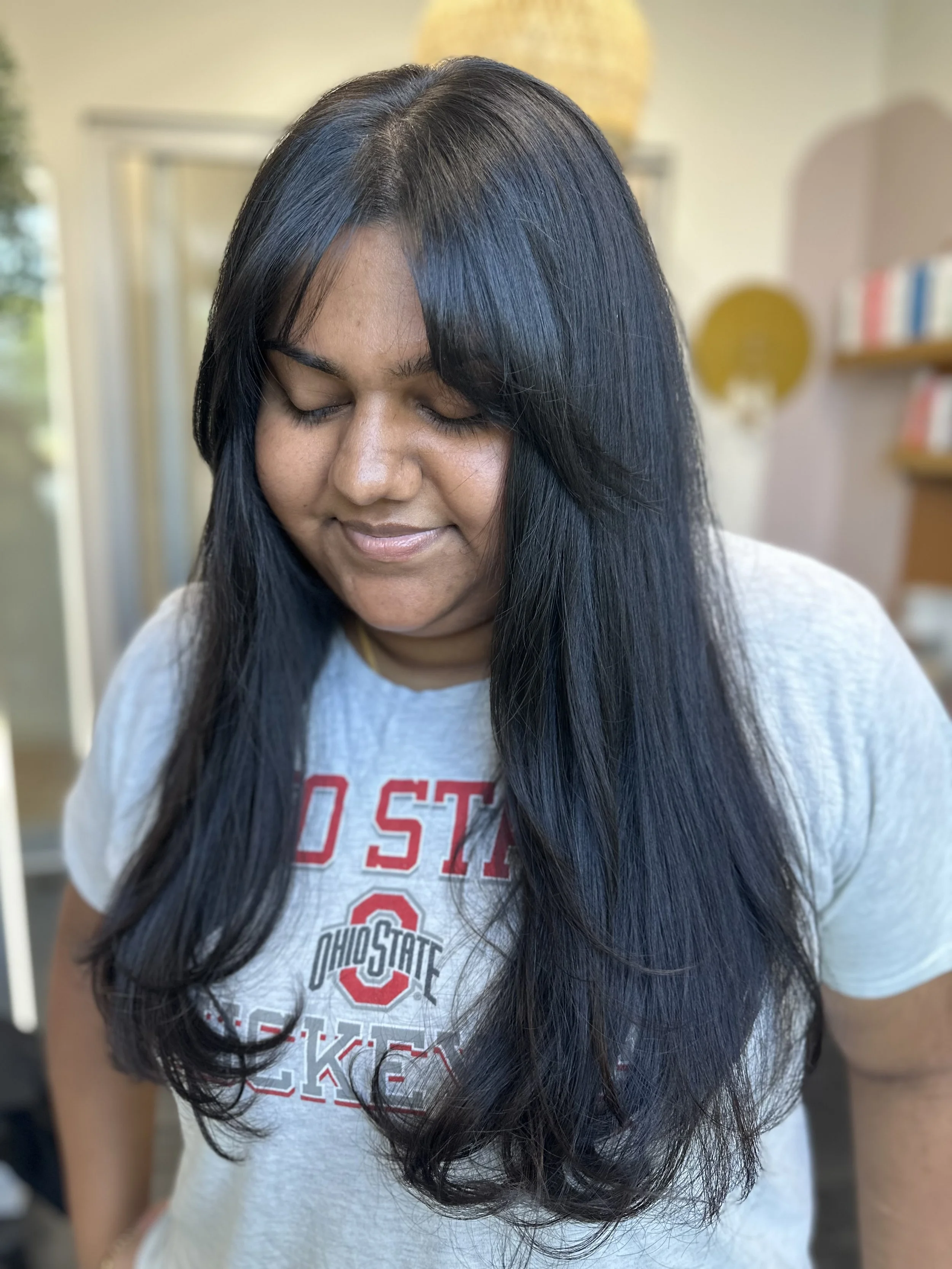 Photo of a client with long, thick, dark hair featuring soft, curtain bangs.