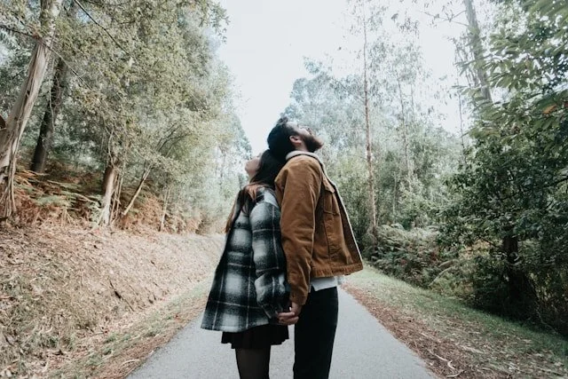 Two people standing back to back on a forest path, depicting emotional distance in relationships