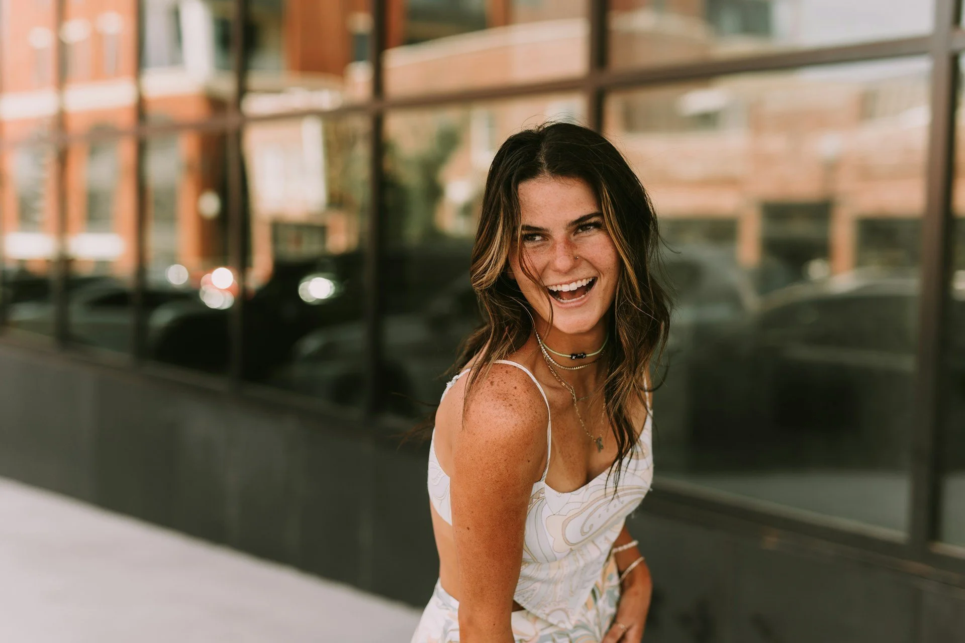Woman smiling at camera in white tank top with soft natural lighting