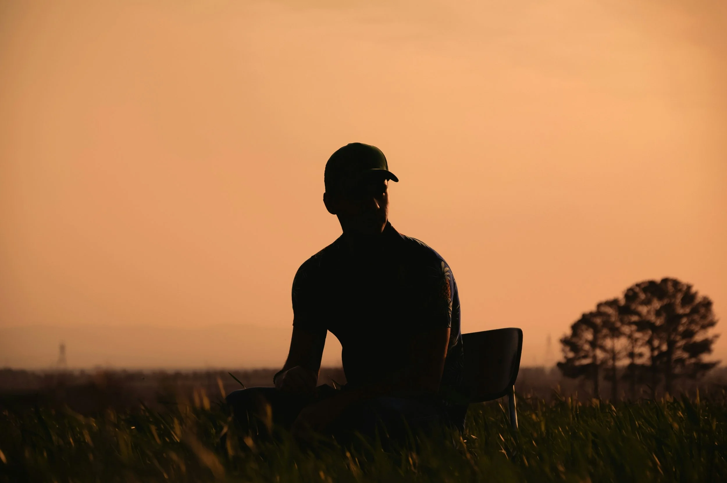 Man sitting in silhouette against a golden sunset, ready to release old patterns and reclaim himself