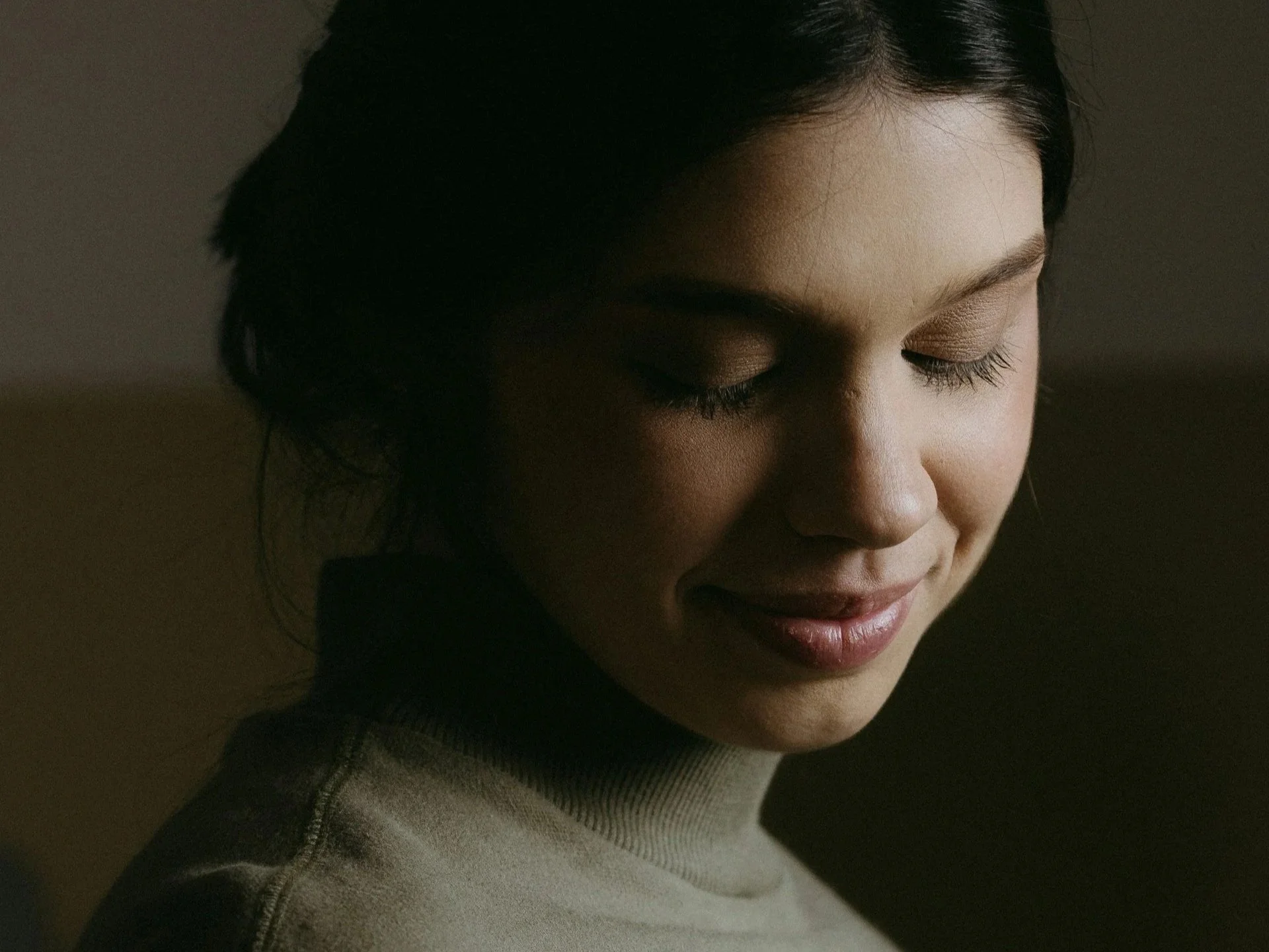 Woman with eyes closed in soft light, turning inward away from external approval