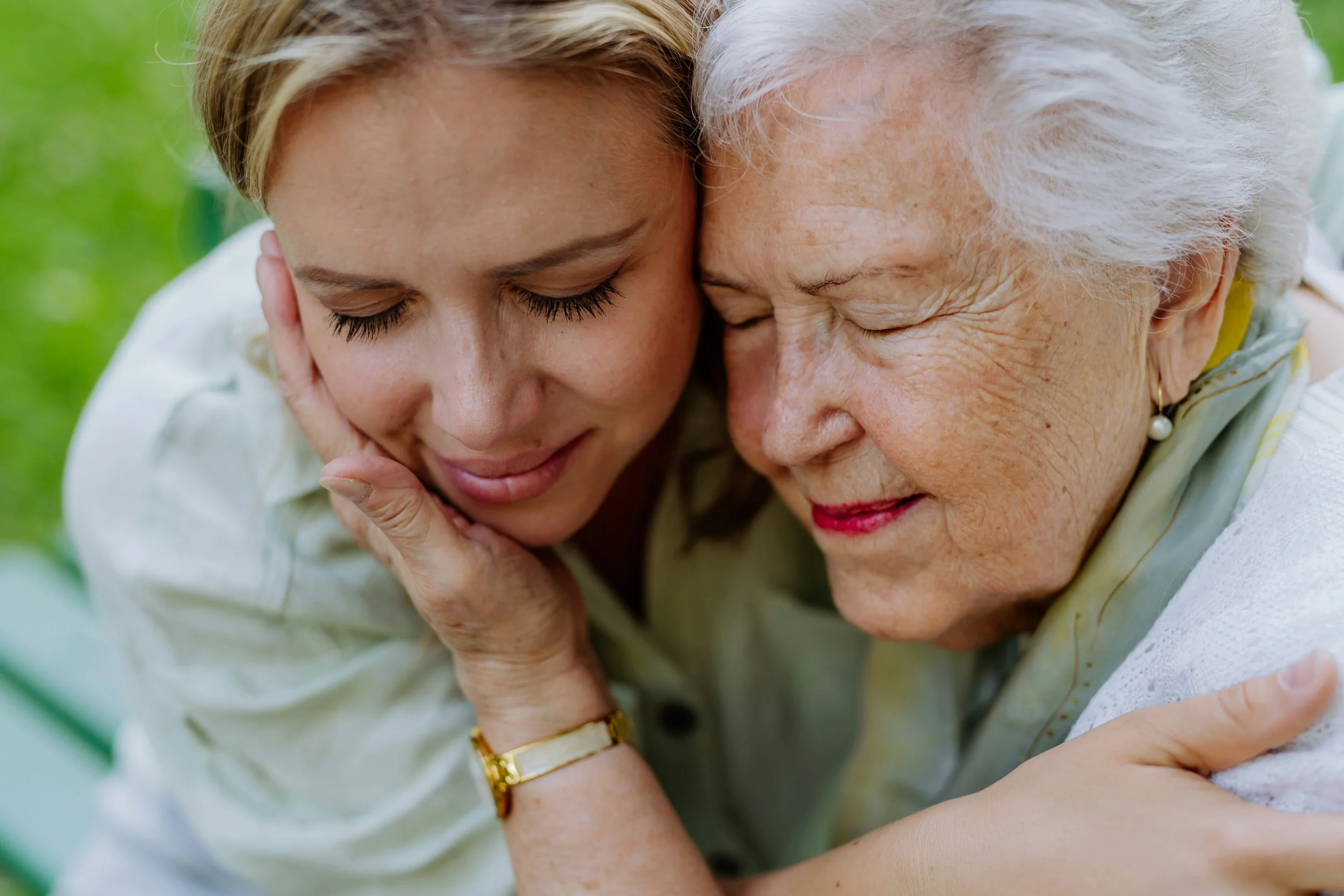 Adult woman embracing elderly woman outdoors with warmth and connection