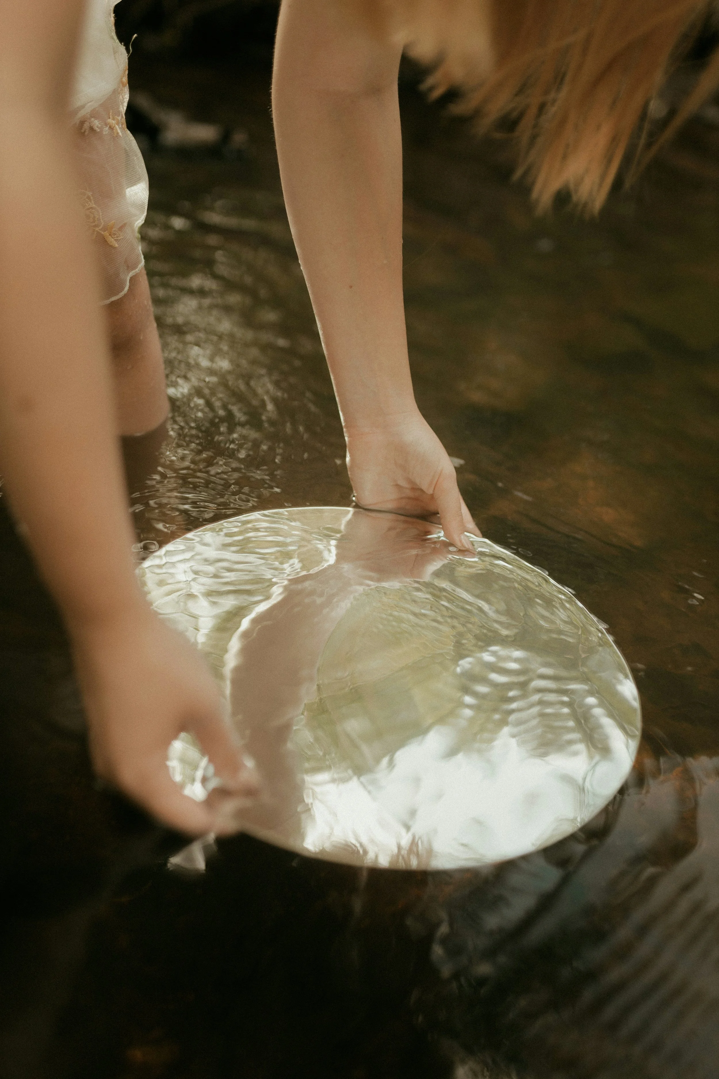 Hands holding a bowl in flowing water, representing the Release and Claim somatic experience