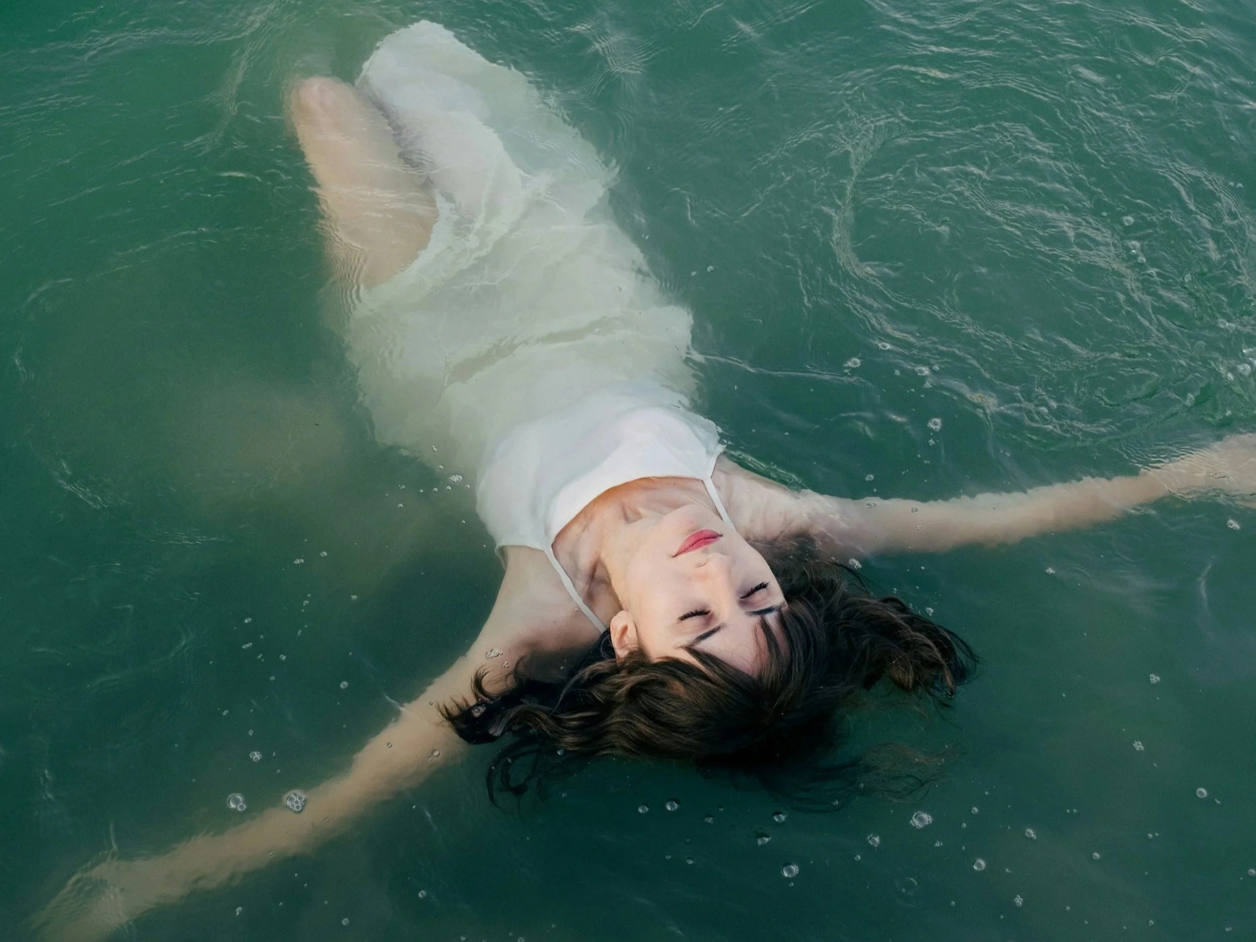 Woman floating on her back in still water, surrendering to the process of recognizing old patterns