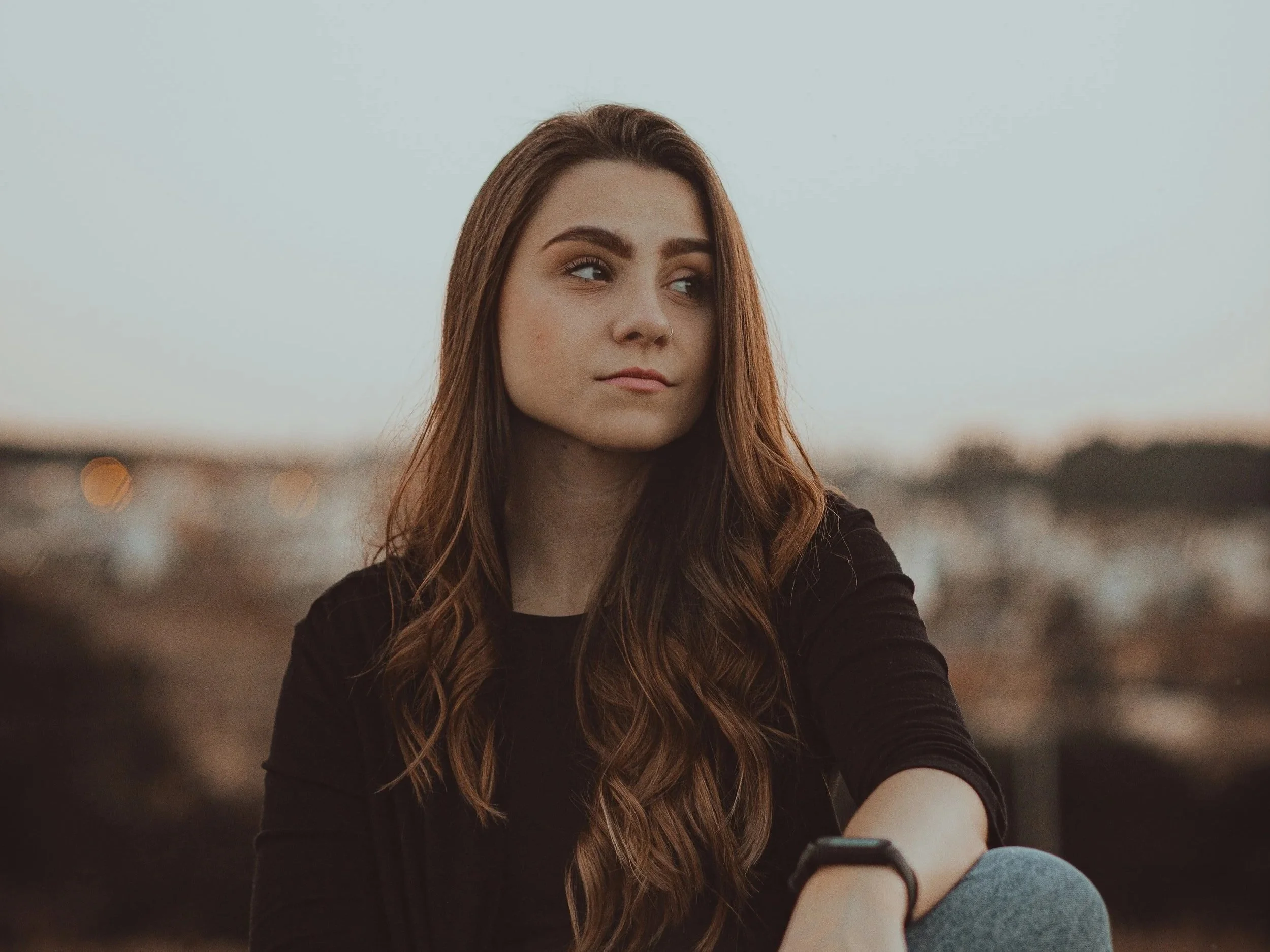 Woman with long hair looking directly into camera, grounded and ready to say no without over-explaining