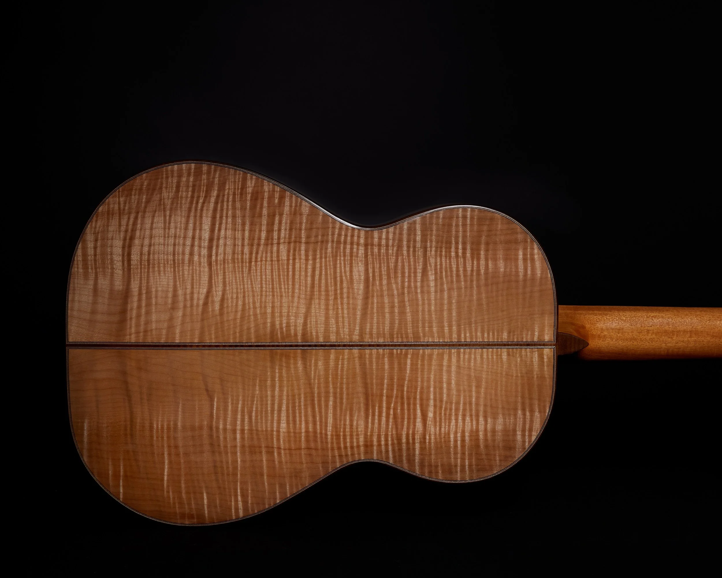 Full rear view of a handmade DeMers classical guitar with a bookmatched flame-maple back, photographed against a black studio background.