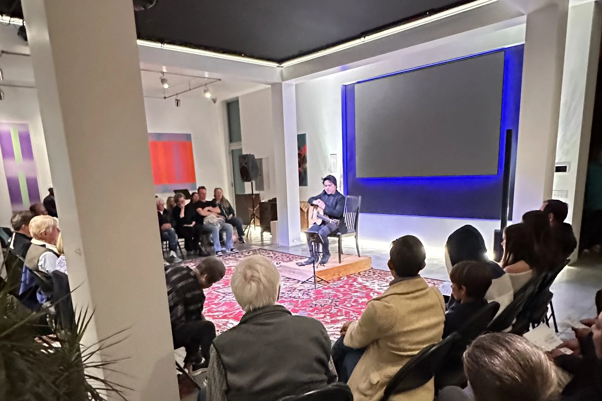 A classical guitarist performing for a seated audience at a Carmel Guitar Society concert in Pacific Grove